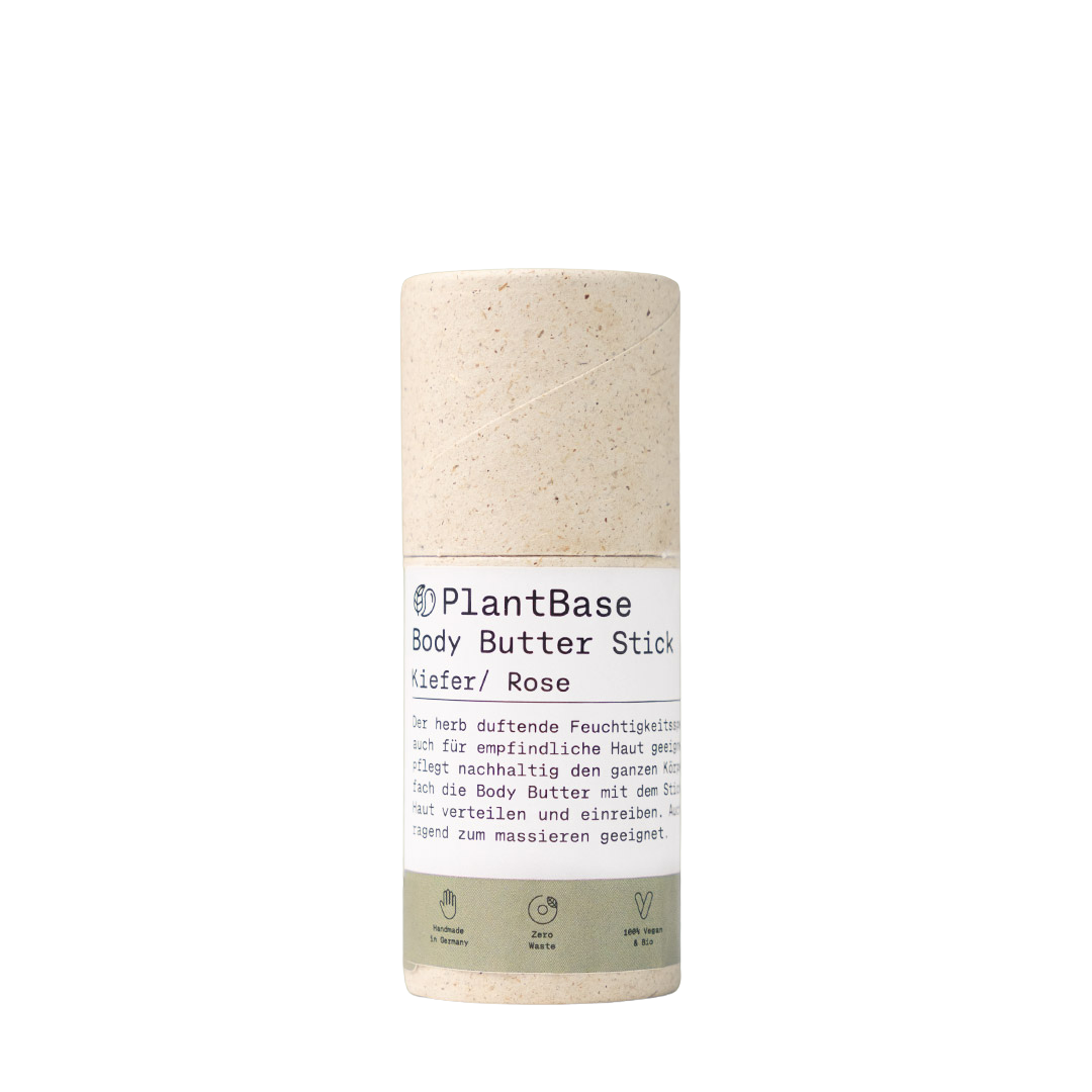 Ein zylindrischer PlantBase Body Butter Stick mit einer beigefarbenen, gesprenkelten, umweltfreundlichen Tube und einem weiß-grünen Etikett mit Produktangaben in deutscher Sprache. Das Produkt ist als vegan und frei von Tierversuchen deklariert.