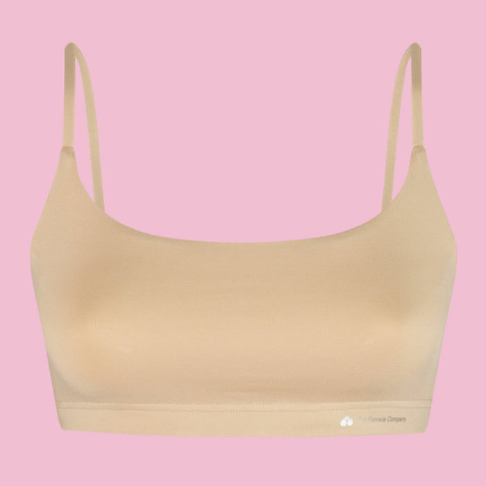 Beigefarbener BH mit Spaghettiträgern vor rosa Hintergrund.