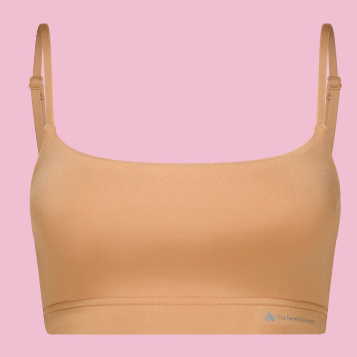 Hautfarbener Bralette-BH vor rosa Hintergrund.