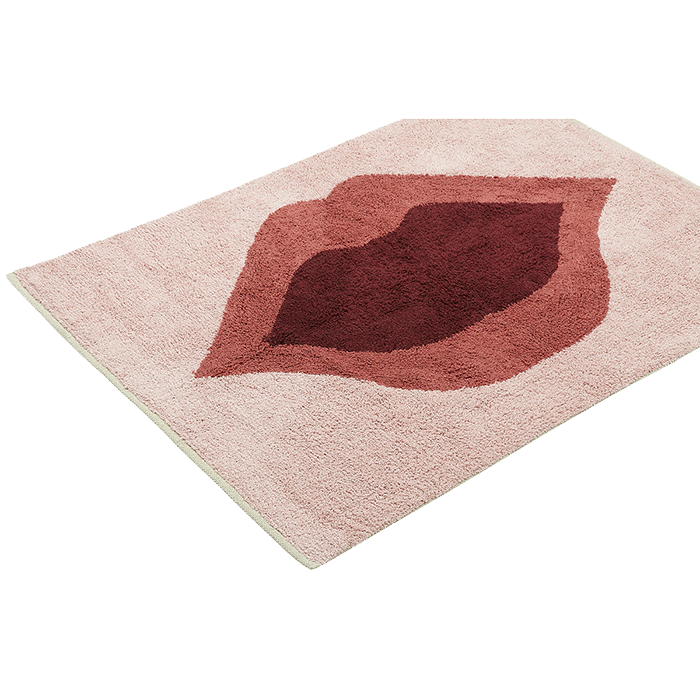 Ein rechteckiger rosafarbener Teppich mit einem großen abstrakten Muster in der Mitte, das an ein Lippenpaar in Rot- und Burgunderfarben erinnert.
