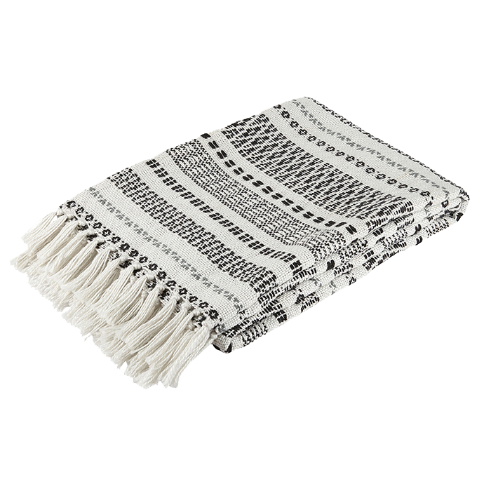 Eine gefaltete gewebte Decke mit schwarzen und weißen geometrischen Mustern und Fransen an einem Ende auf weißem Hintergrund.