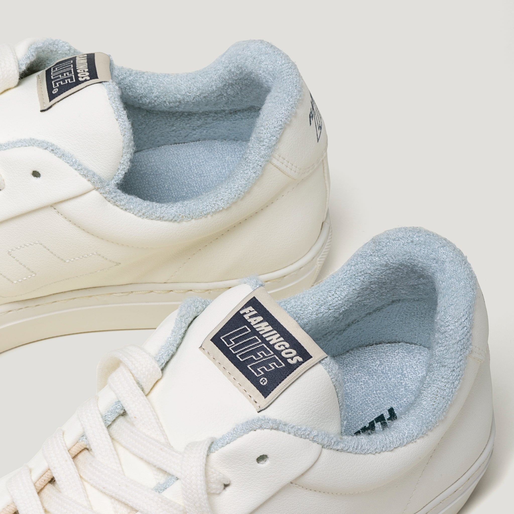 Weiße Sneaker mit hellblauem Innenfutter und einem Label mit der Aufschrift "FLAMINGOS LIFE".