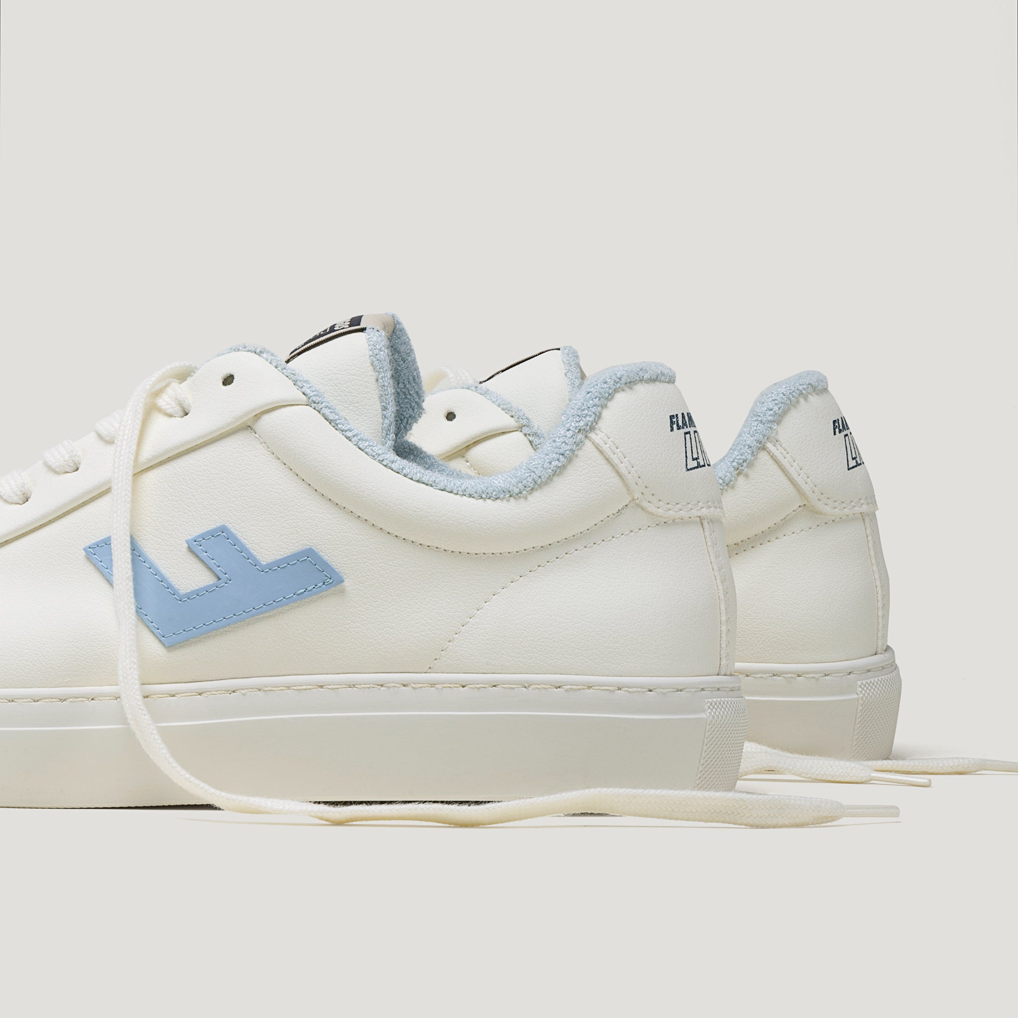 Weiße Sneaker mit blauen Details und flauschigem Innenfutter, seitlich und von hinten fotografiert.