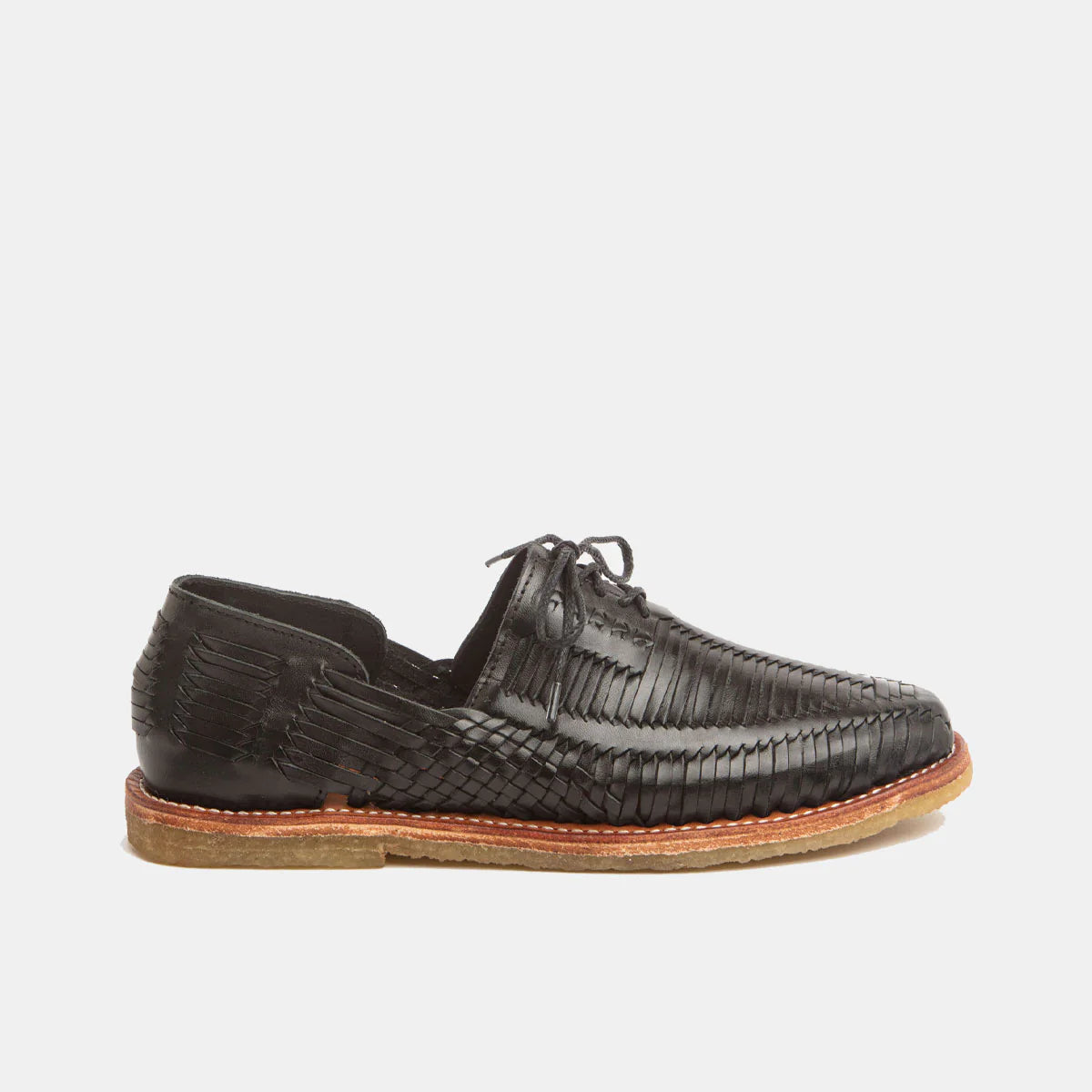 Ein schwarzer Schuh aus gewebtem Leder mit Schnürung, sichtbaren Nähten und hellbrauner Sohle, der auf einem schlichten weißen Hintergrund steht.
