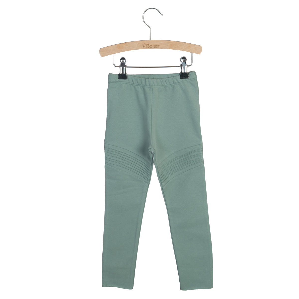 Hellgrüne Kinderleggings mit gerippten Details an den Knien, ausgestellt auf einem Holzbügel vor weißem Hintergrund.