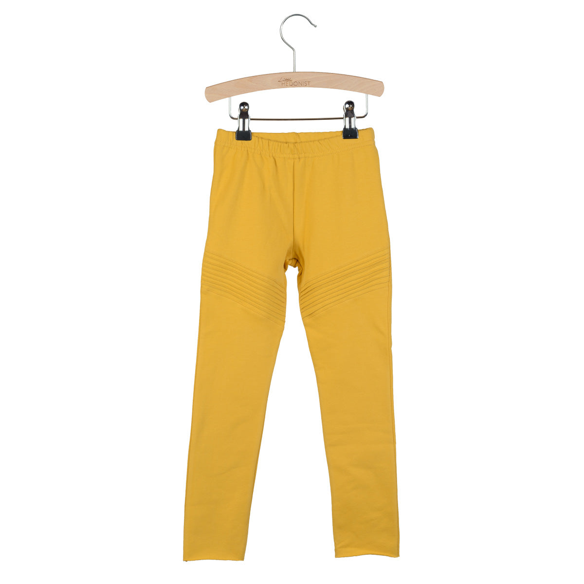 Ein Paar gelbe Leggings mit gerippten Details über den Knien, ausgestellt auf einem Holzbügel vor weißem Hintergrund.