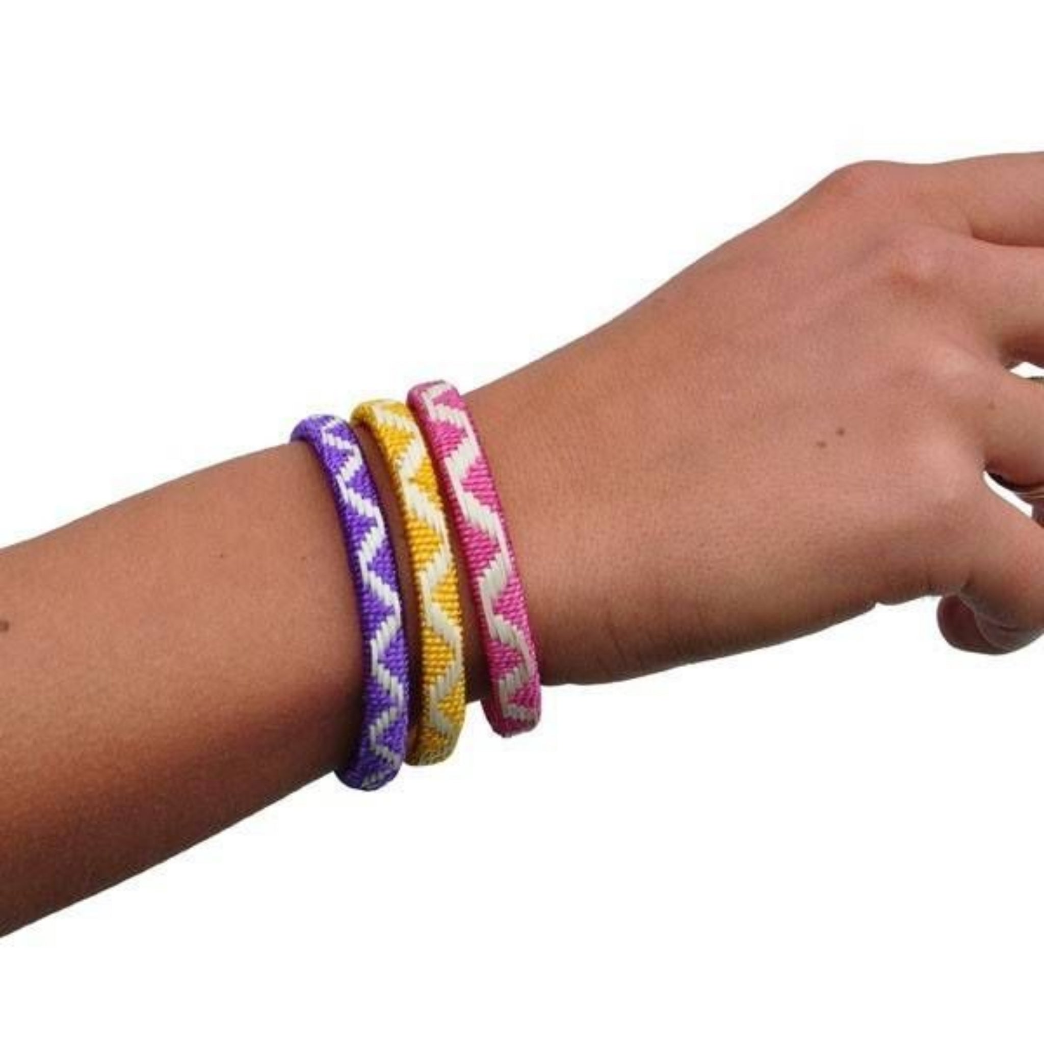 Eine Hand trägt drei gewebte Freundschaftsarmbänder in Lila, Gelb und Rosa mit weißen Zickzackmustern vor einem schlichten weißen Hintergrund.