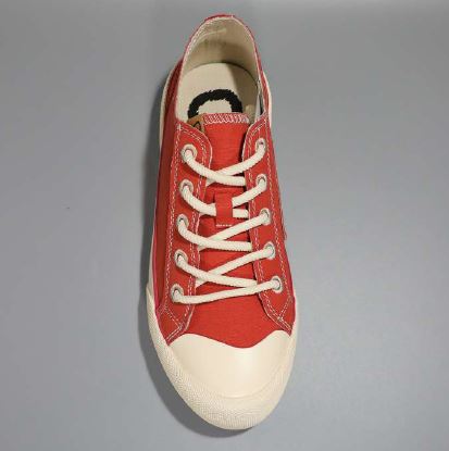 Roter Sneaker mit weißen Schnürsenkeln auf grauem Hintergrund.