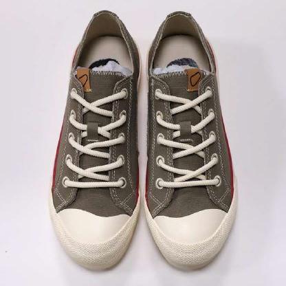 Zwei graue Turnschuhe mit weißen Schnürsenkeln und beige Zehenkappen auf weißem Hintergrund.