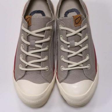 Graue Sneaker mit weißer Sohle und weißen Schnürsenkeln auf weißem Hintergrund.