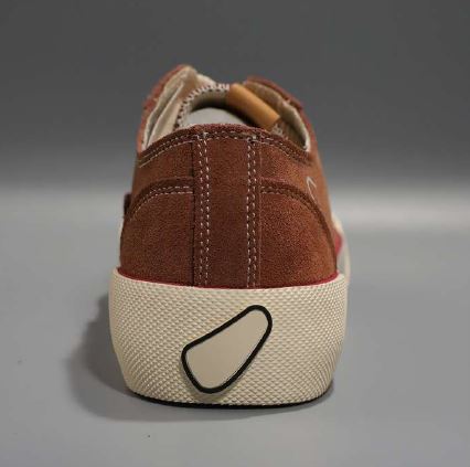 Rückansicht eines braunen Wildlederschuhs mit einer cremefarbenen Sohle und einem schwarzen Motiv.