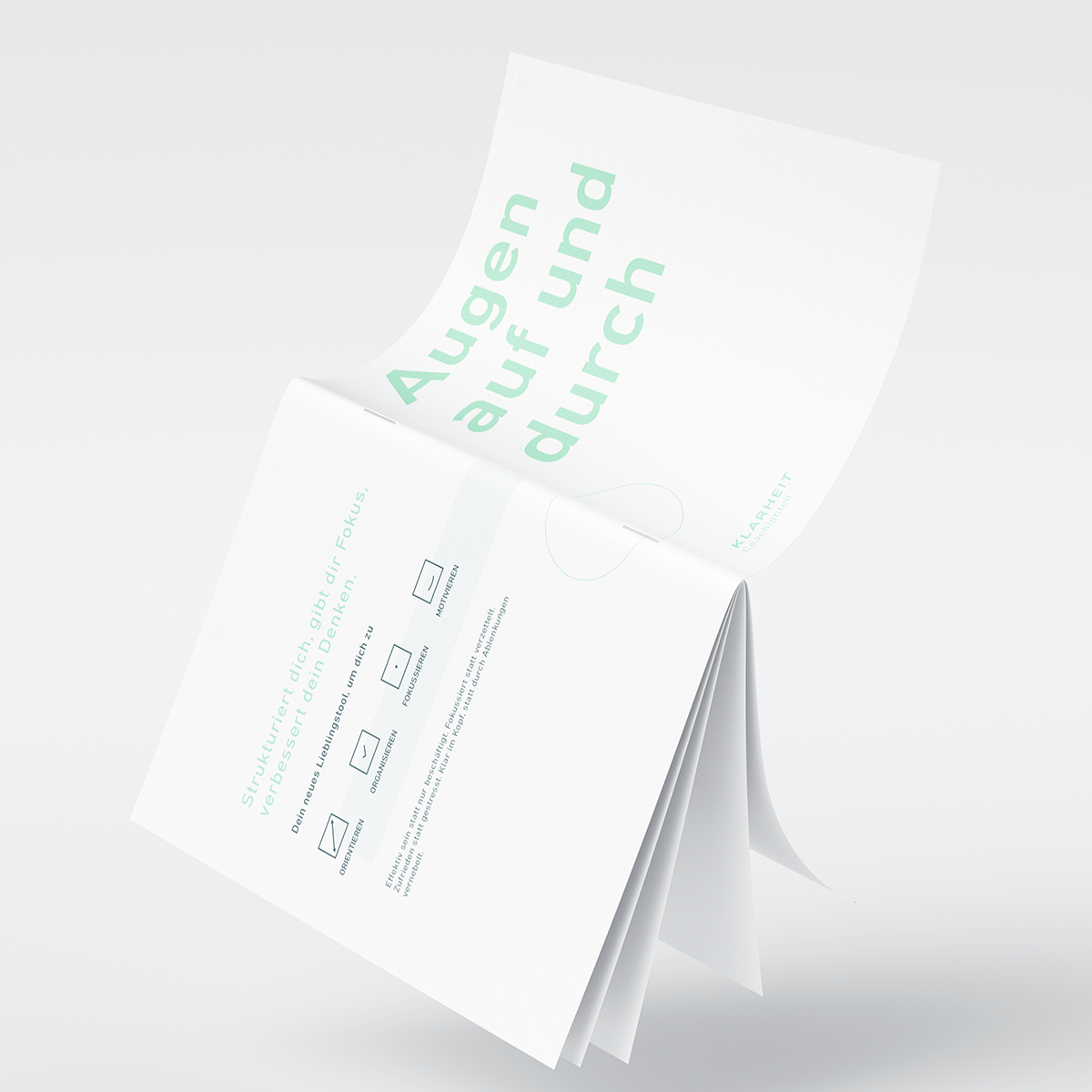 Offenes Notizbuch mit dem Text „Augen auf und durch“, auf hellem Hintergrund.