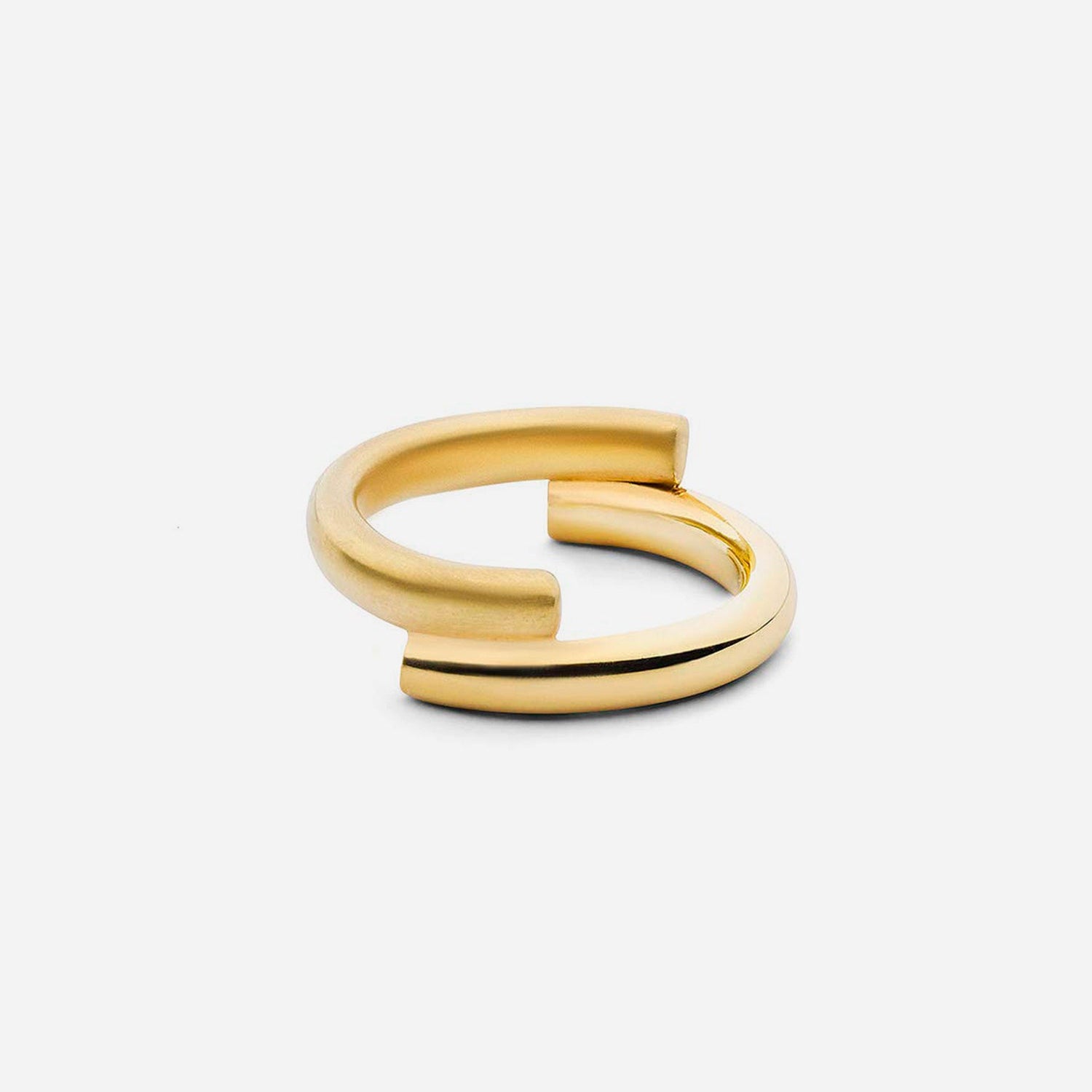 Ein minimalistischer, offener Goldring mit modernem, asymmetrischem Design, der auf einem schlichten, hellen Hintergrund gezeigt wird.