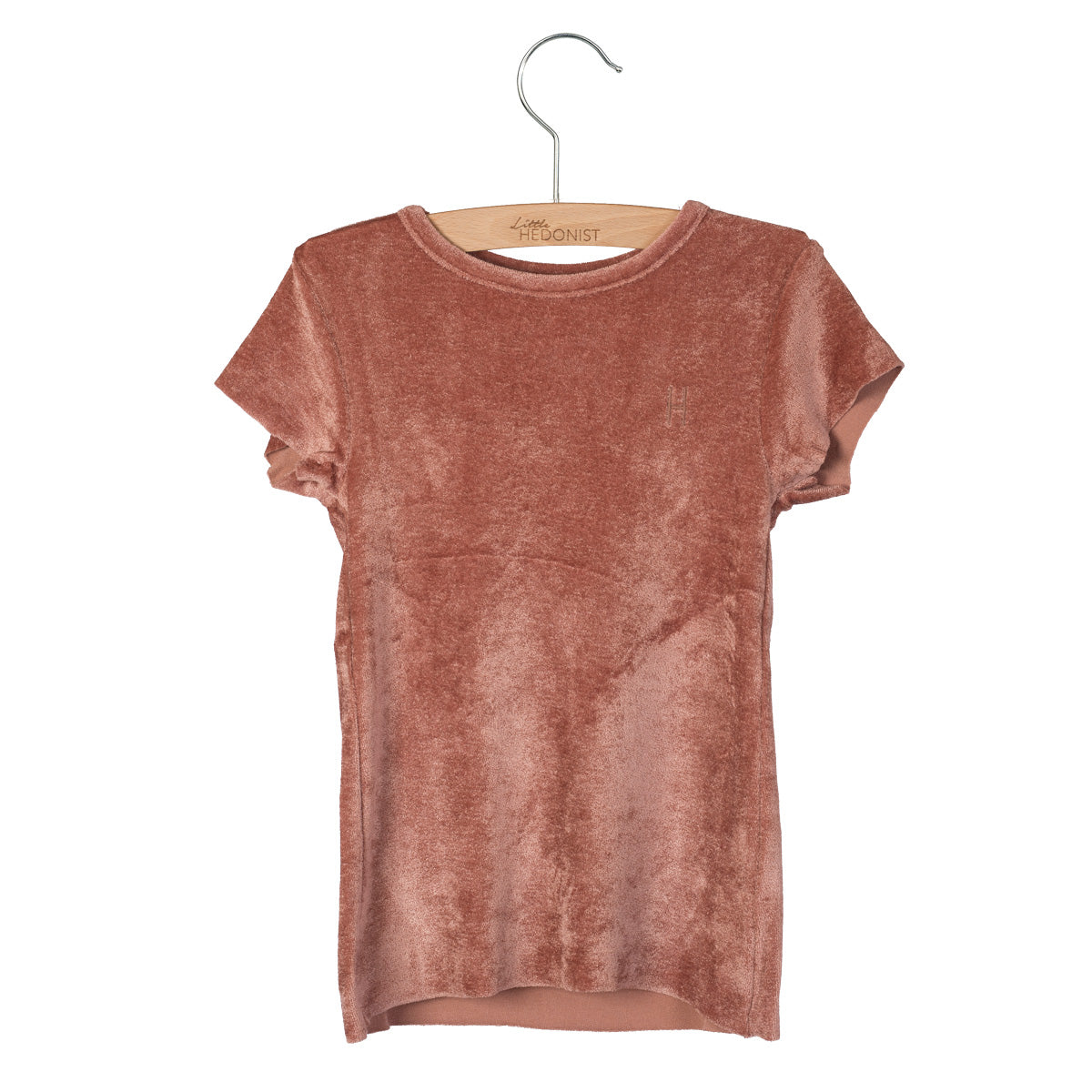 Ein kurzärmeliges, staubrosa Samt-T-Shirt ist auf einem Holzbügel vor weißem Hintergrund ausgestellt.