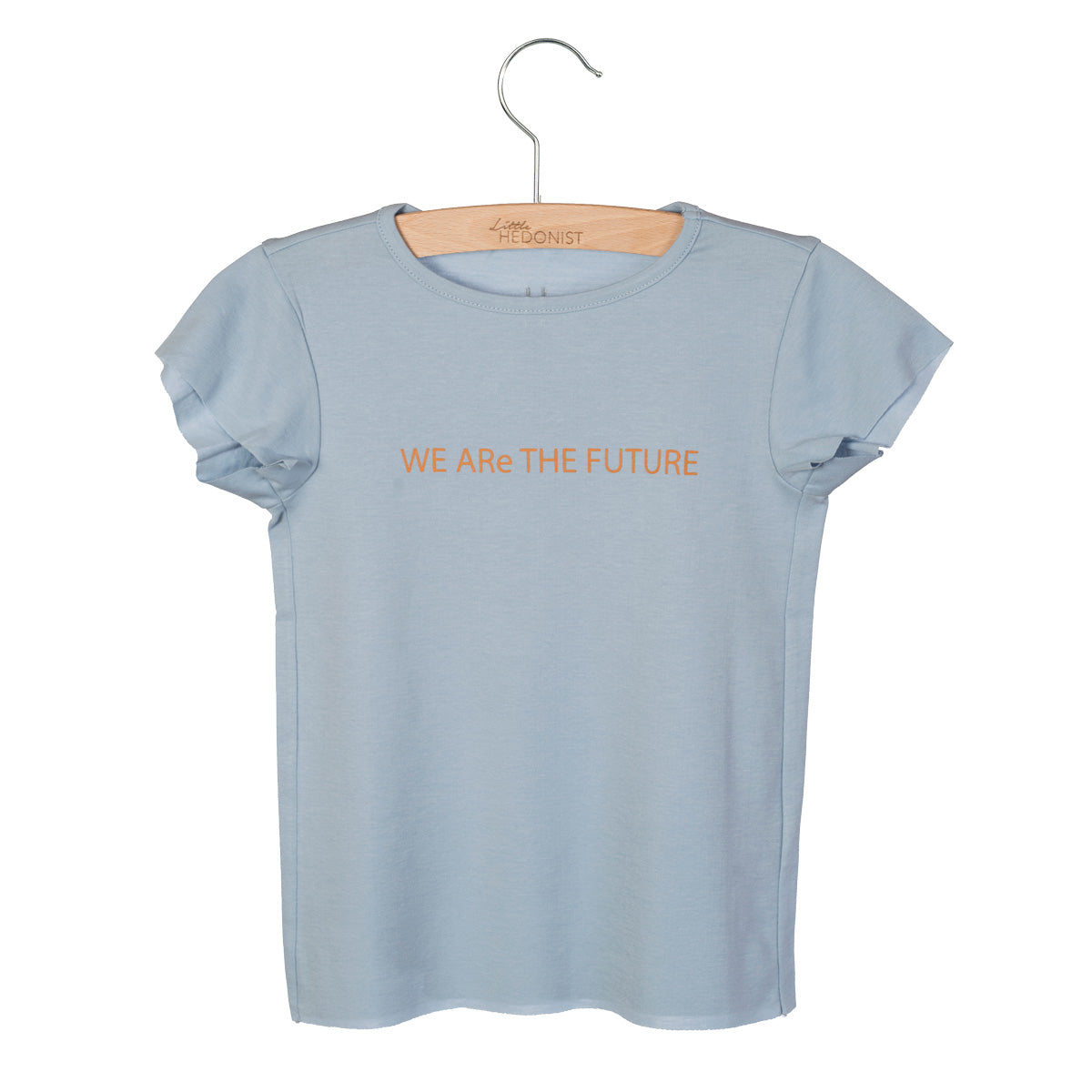 Ein hellblaues, kurzärmeliges T-Shirt auf einem Holzbügel, mit dem Schriftzug WE ARe THE FUTURE in orangefarbener Schrift auf der Brust.