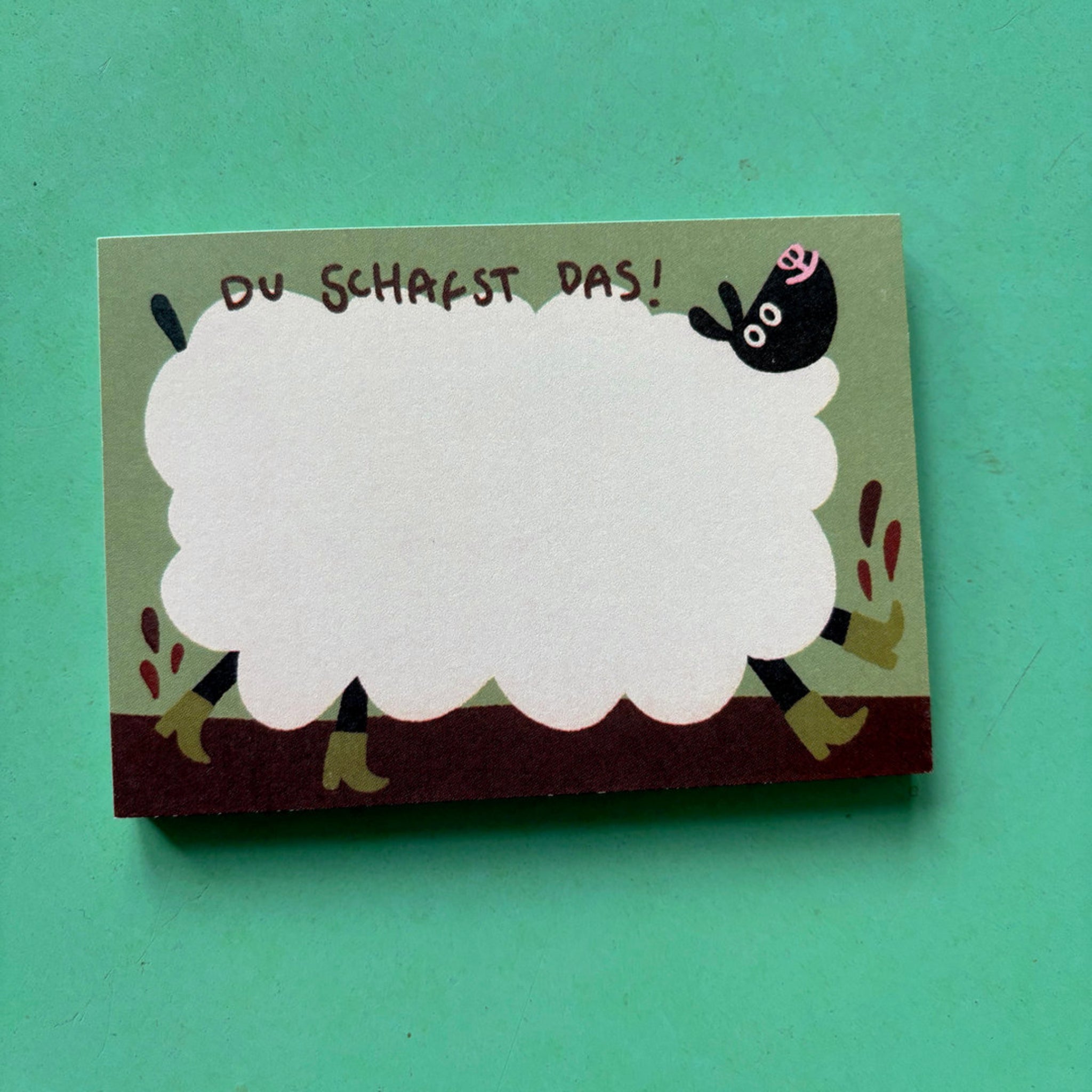 Eine Karte mit einem gezeichneten Schaf und der Aufschrift "Du schaffst das!" auf einem grünen Hintergrund.
