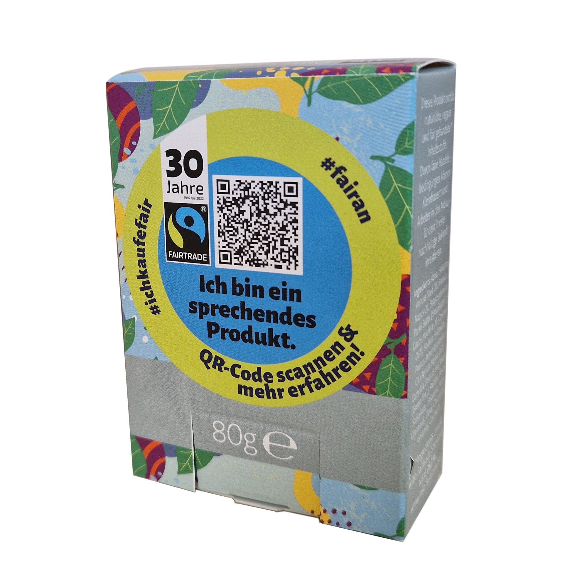 Eine farbenfrohe rechteckige Box mit deutschem Text, darunter Ich bin ein sprechendes Produkt, ein QR-Code, "Fairtrade" und "30 Jahre". Die Schachtel hat ein Gewicht von 80 g und ist mit lebhaften abstrakten Mustern verziert.