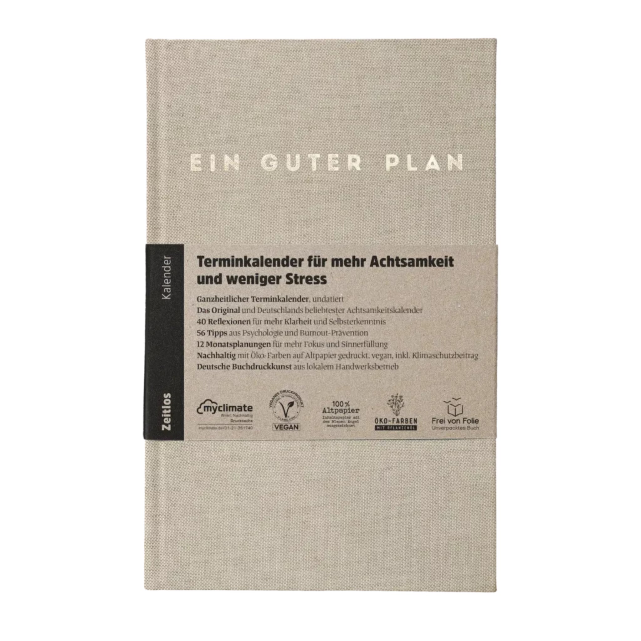 Ein graues Notizbuch mit der Aufschrift "EIN GUTER PLAN" und einem Informationsband über Achtsamkeit und Nachhaltigkeit.