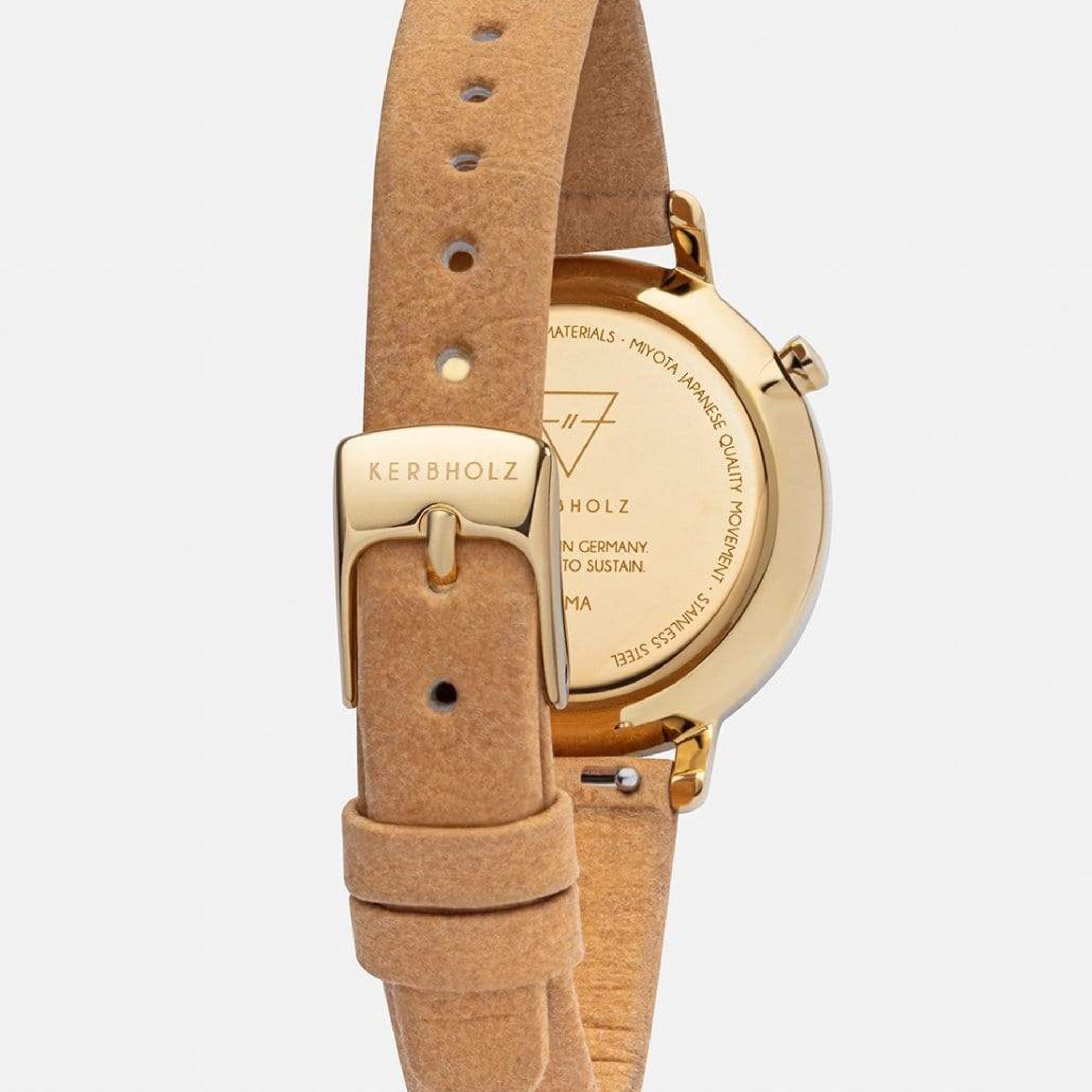 Rückseite einer Armbanduhr mit einem beige Lederriemen und goldfarbener Edelstahlschließe, auf der "Kerbholz" steht.