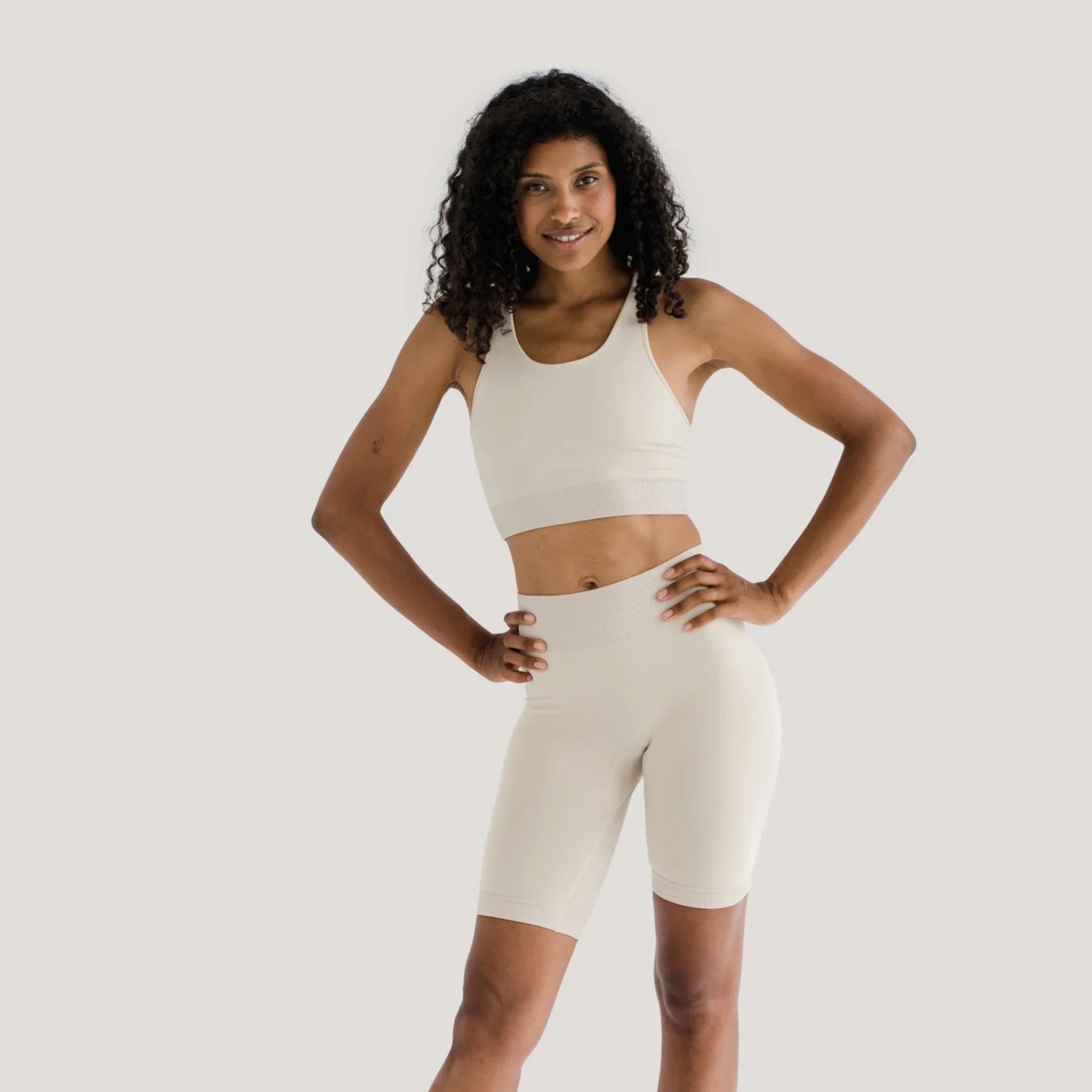 Person in cream sportswear posing confidently against a neutral background.