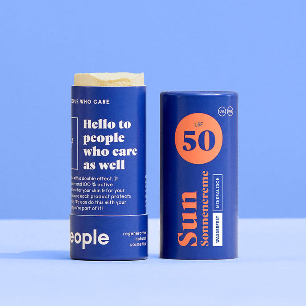 Zwei blaue zylindrische Sonnencremebehälter mit der Aufschrift Sun Somercreen mit SPF 50 stehen aufrecht auf einer blauen und hellblauen Fläche vor einem blauen Hintergrund. Ein Behälter ist geöffnet und zeigt den Sonnenschutzstift darin.