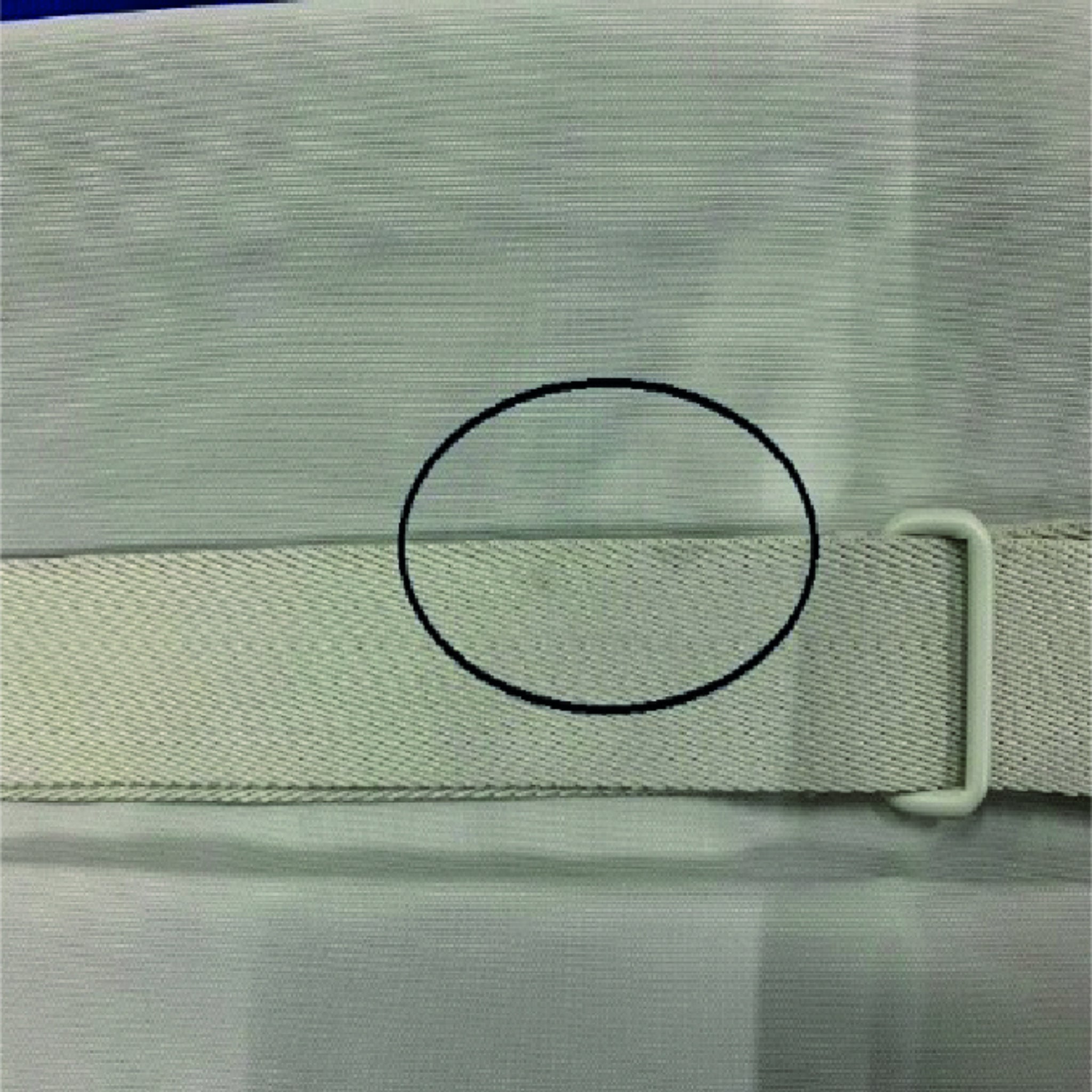 Ein Stoffband mit einer Metallschnalle, umgeben von einem schwarzen Kreis auf hellgrauem Hintergrund.