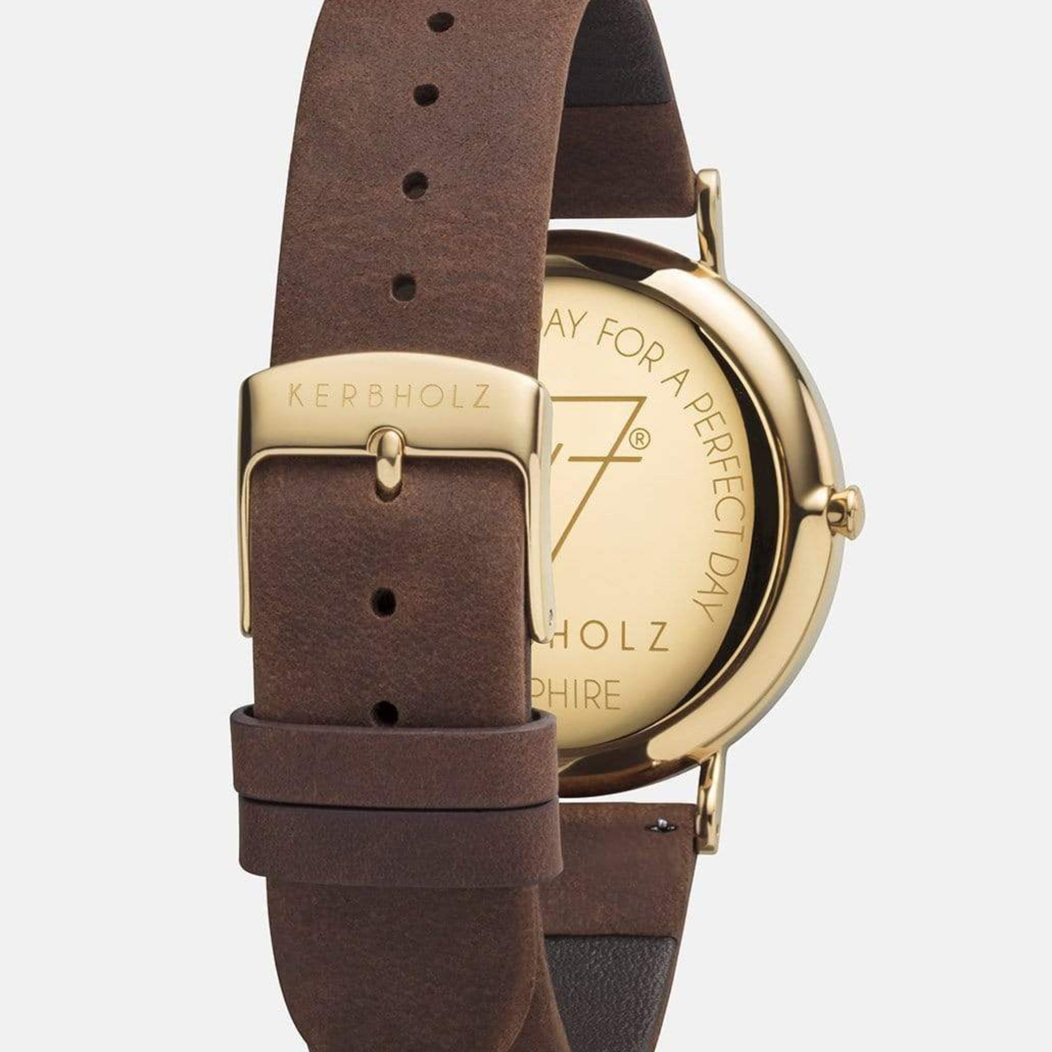Nahaufnahme einer Armbanduhr mit einem braunen Lederarmband und einer goldenen Gehäuserückseite mit Gravur.