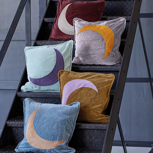 Fünf dekorative Kissen mit Mondmotiven liegen auf einer Metalltreppe, in verschiedenen Farben arrangiert.
