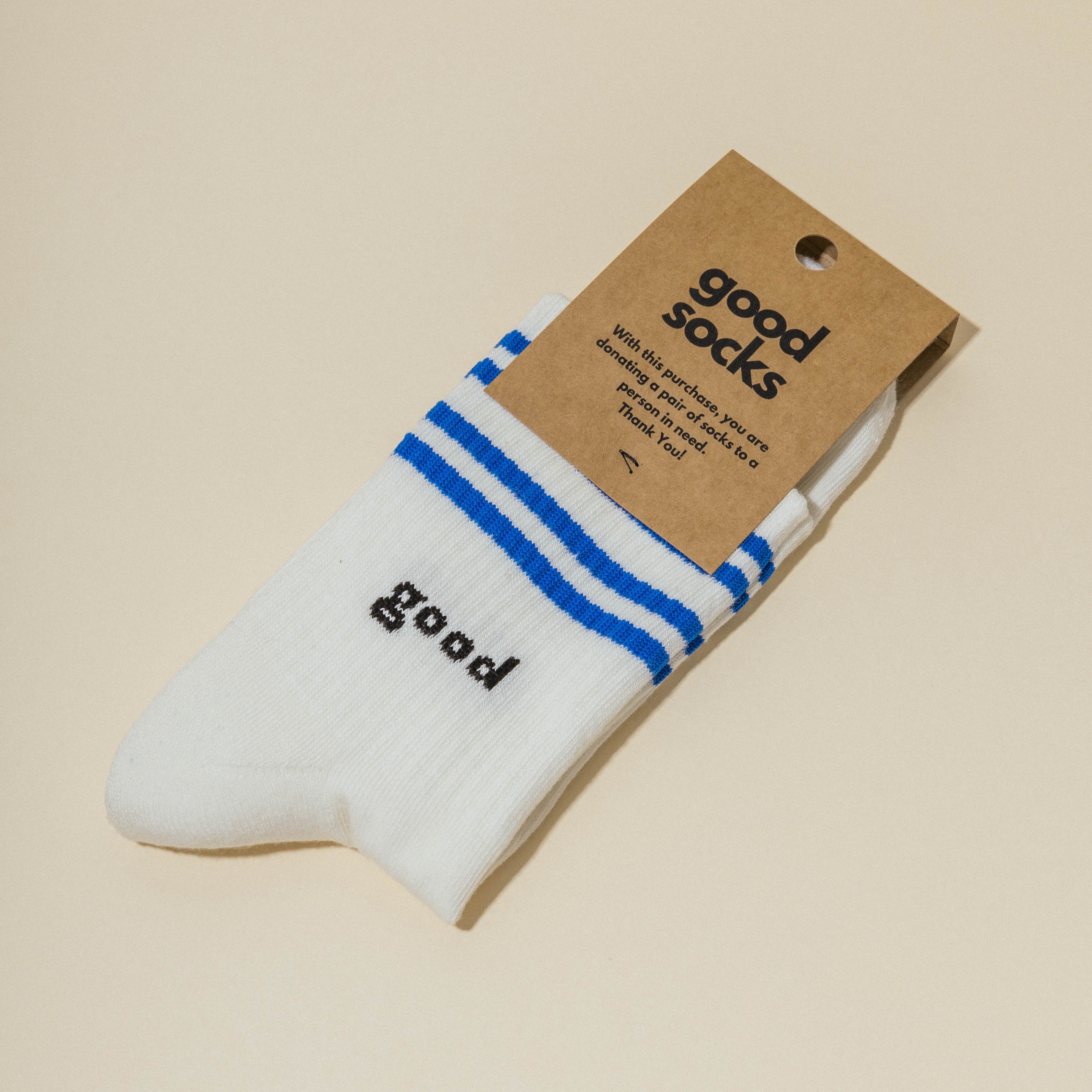 Weiße Socken mit blauen Streifen und dem Wort "good", verpackt mit einem braunen Etikett mit Aufschrift "good socks".