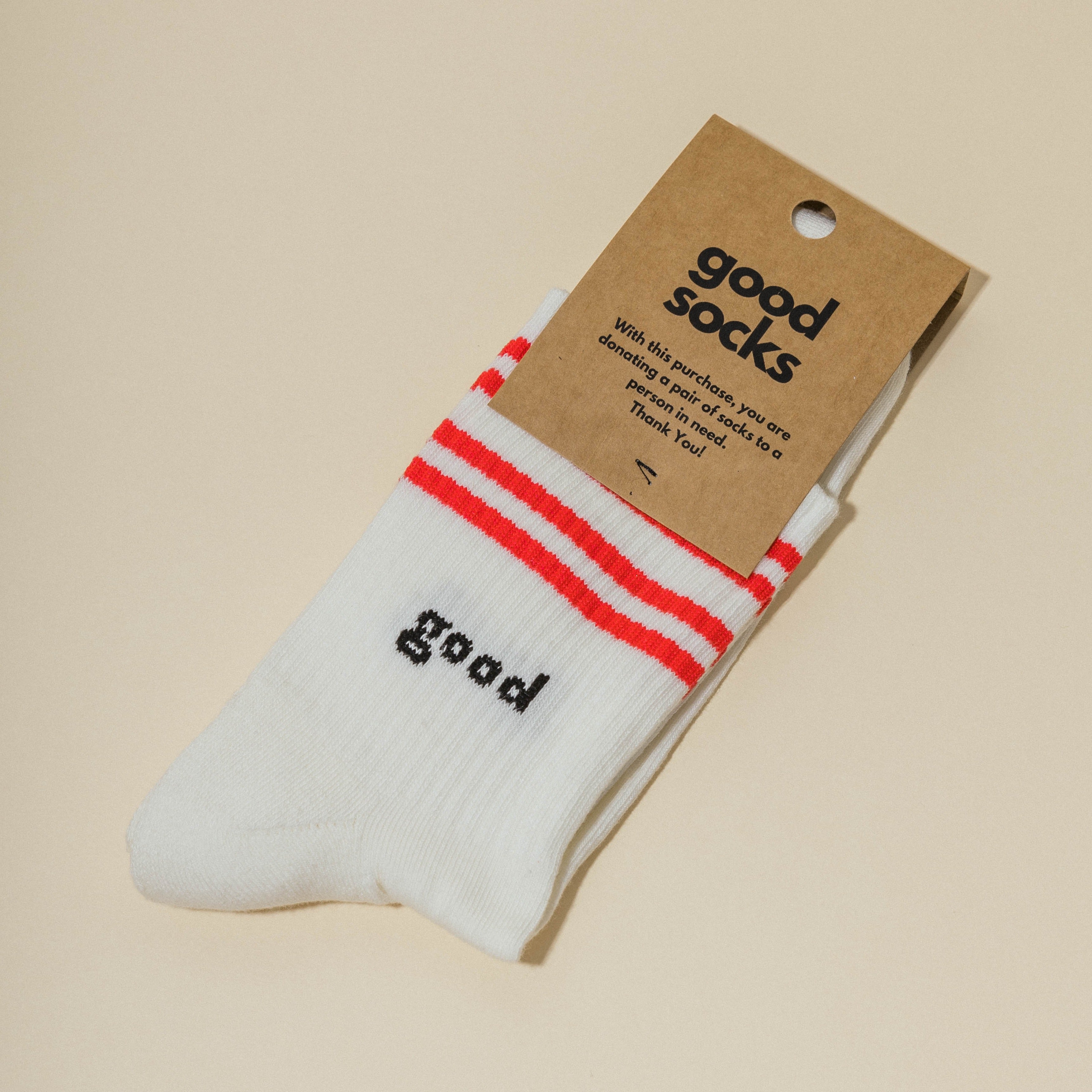 Weiße Socken mit roten Streifen und dem Wort "good", an einem Etikett mit der Aufschrift "good socks" befestigt.