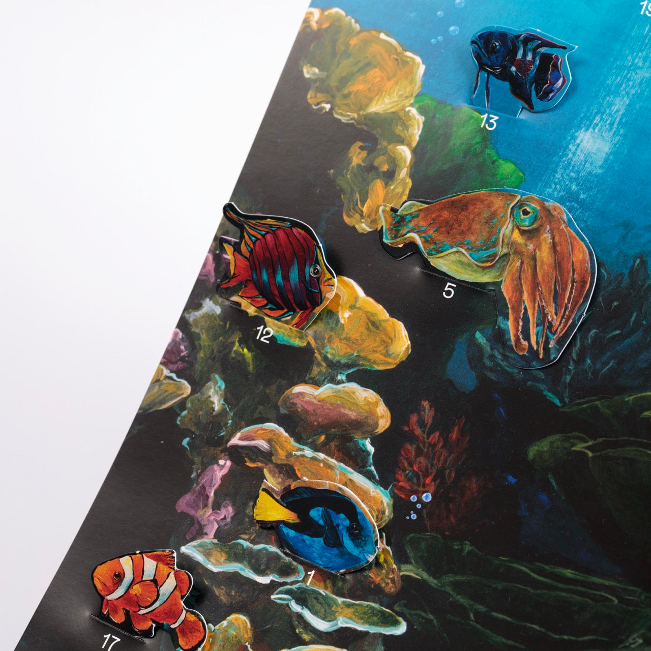 Eine farbenfrohe Illustration zeigt verschiedene nummerierte Meerestiere, darunter einen roten Fisch (12), einen Tintenfisch (5), einen Clownfisch (1) und einen Blautang (11), vor dem Hintergrund eines Korallenriffs.