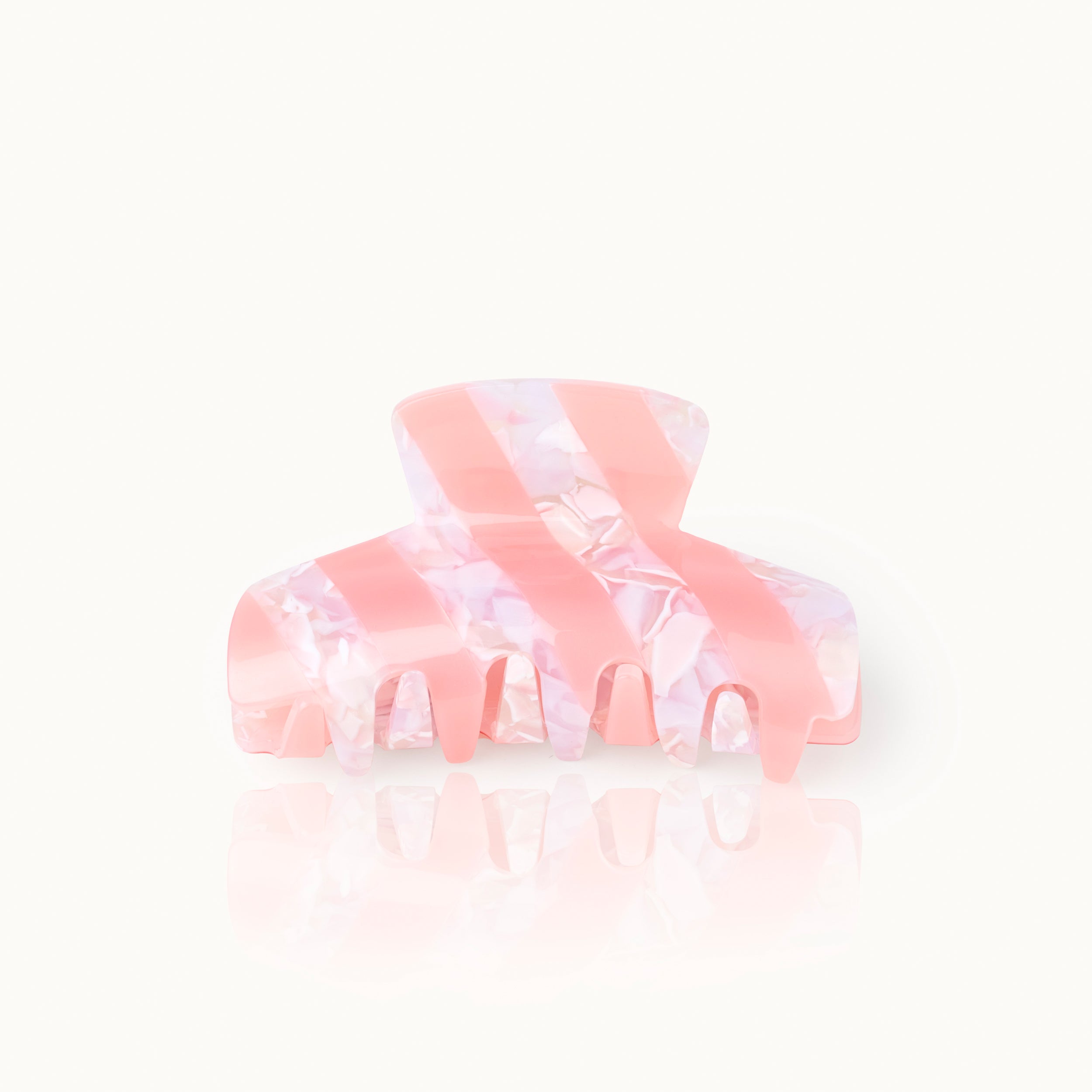 Rosafarbene Haarspange mit weißem Marmor-Muster und reflektierender Oberfläche, auf hellem Hintergrund.