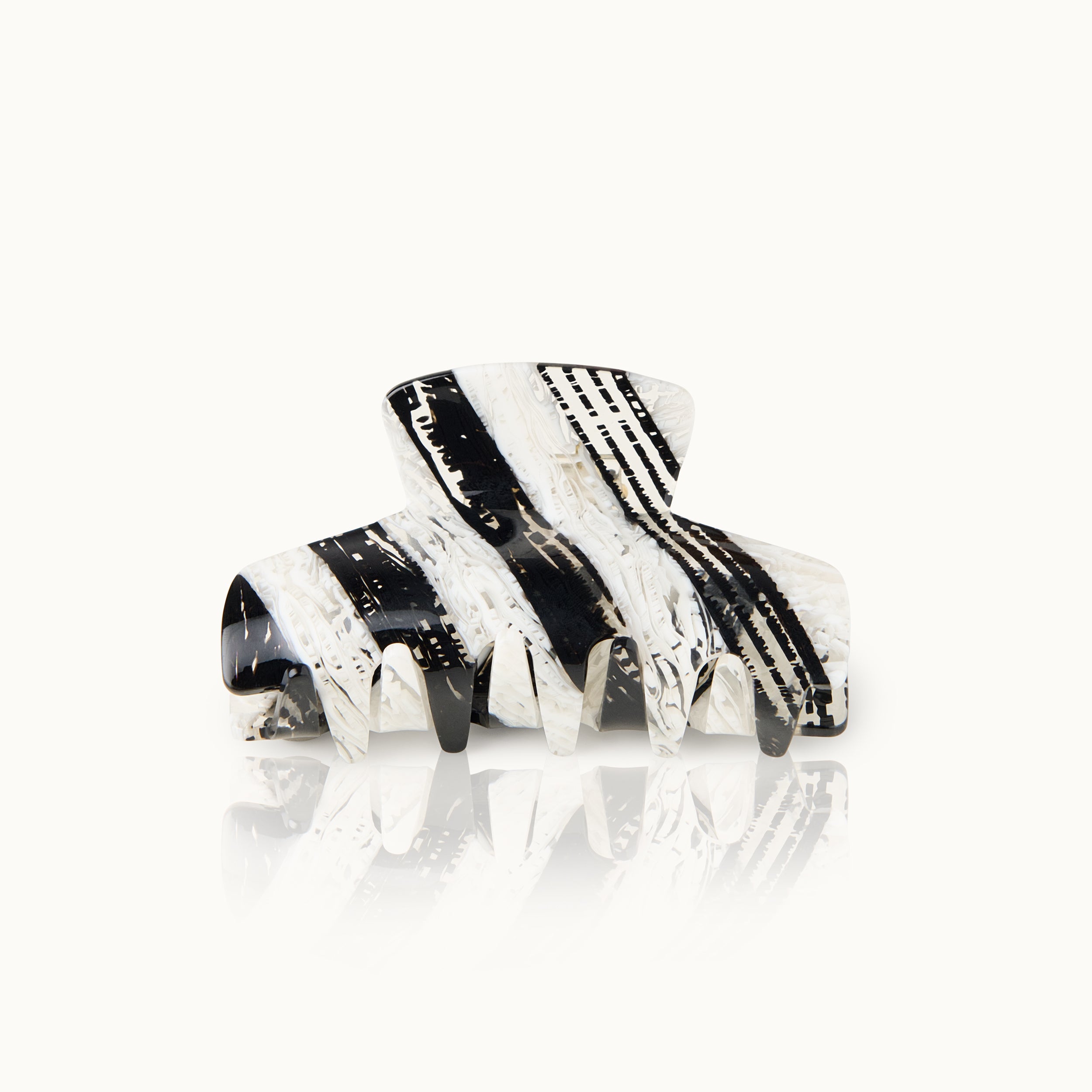 Schwarz-weiß gemusterte Haarklammer mit reflektierender Oberfläche auf weißem Hintergrund.