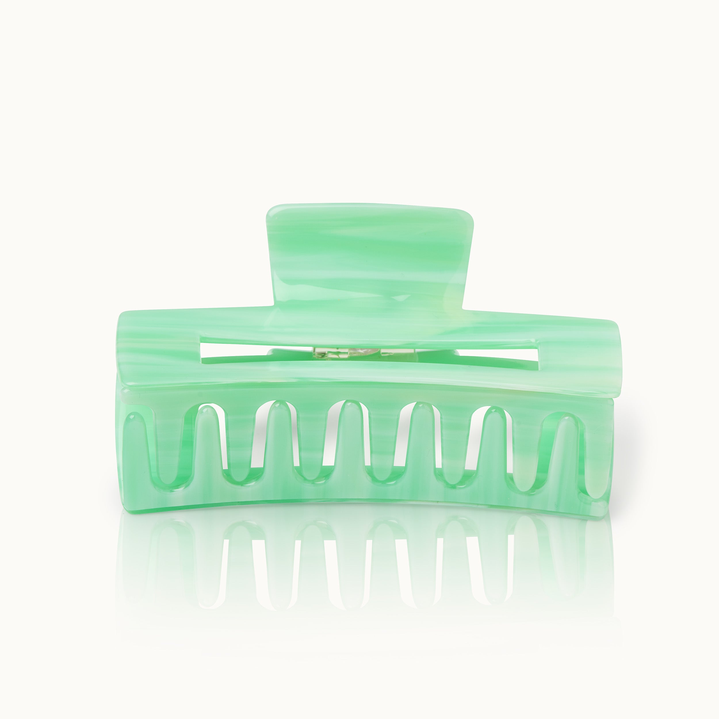 Grüne Haarspange aus Kunststoff mit reflektierendem Effekt auf weißem Hintergrund.