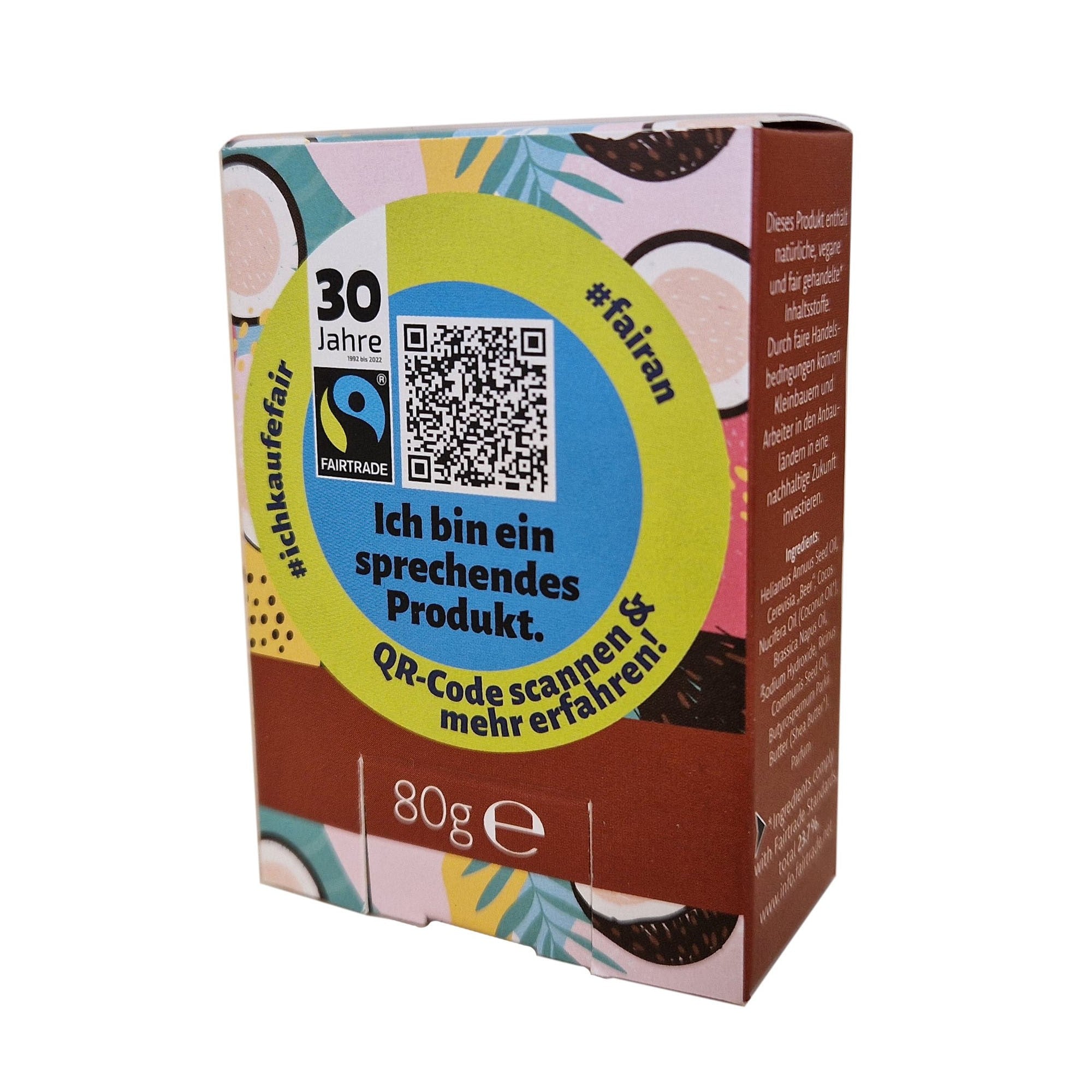 Eine bunte 80g-Dose mit einem QR-Code auf der Vorderseite, deutschem Text und Fairtrade-Logo. Der Text lautet: Ich bin ein sprechendes Produkt. QR-Code scannen & mehr erfahren! mit dekorativen Mustern rund um die Schachtel.