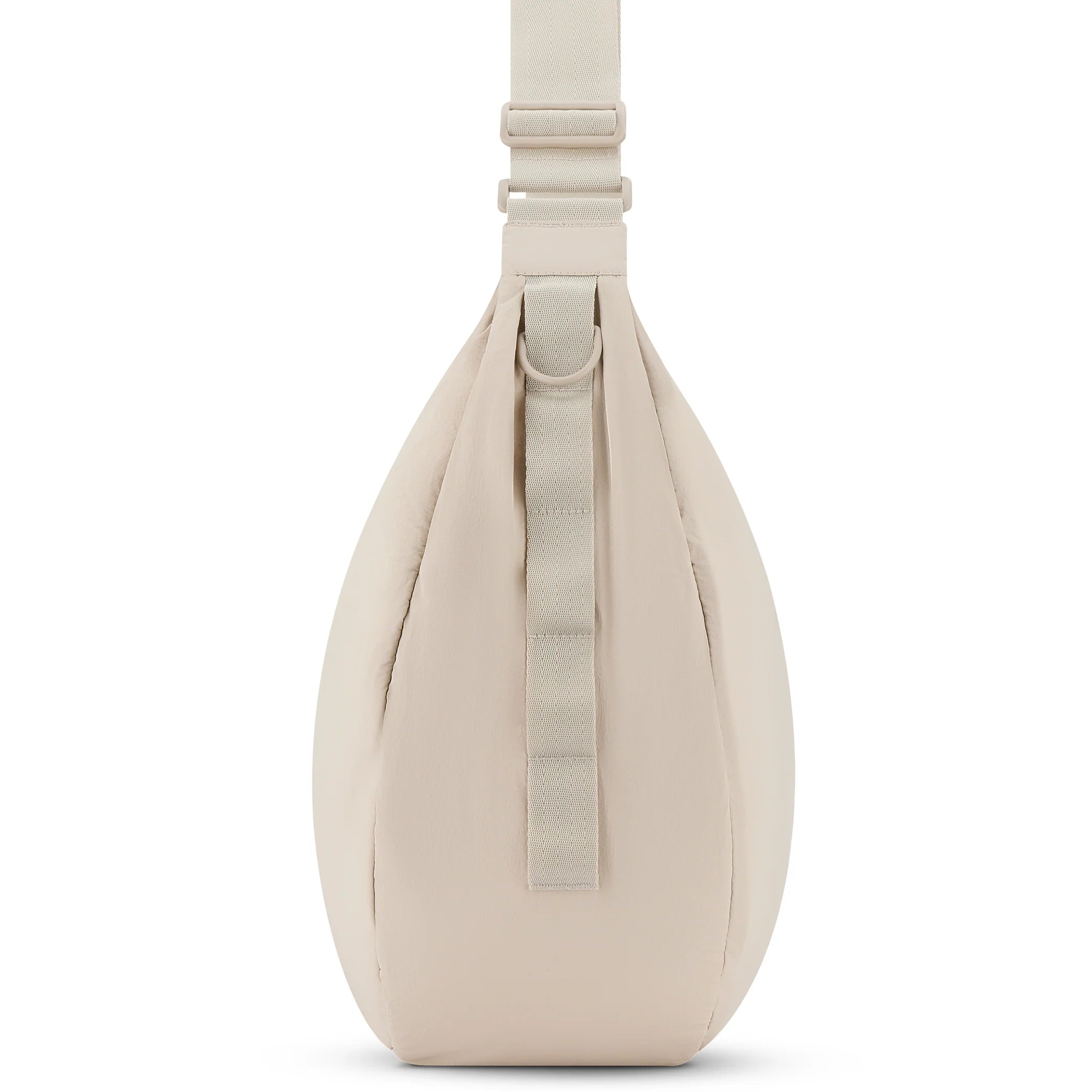 Beigefarbene, tropfenförmige Slingtasche in der Seitenansicht, mit verstellbarem Riemen und vertikaler Stoffschleife auf der Vorderseite.