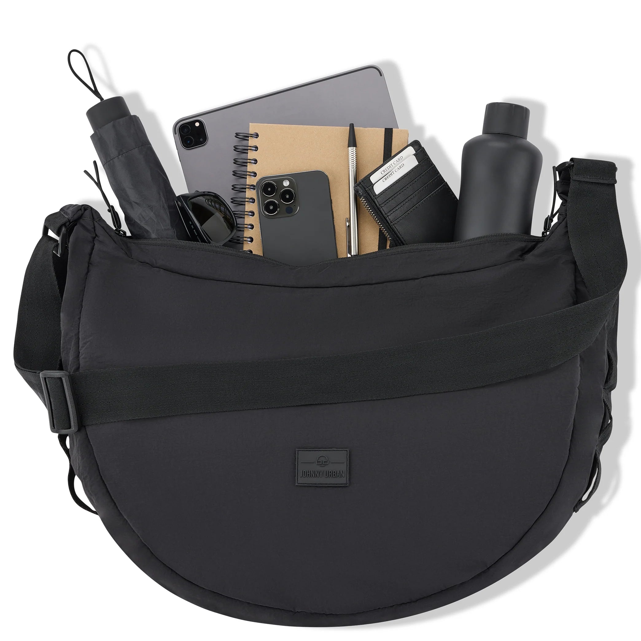 Eine schwarze Umhängetasche, gefüllt mit Gegenständen wie einem schwarzen Regenschirm, einem Tablet, Notizbüchern, einem Smartphone, einem Stift, einem Portemonnaie und einer schwarzen Wasserflasche, alles ordentlich angeordnet und von oben sichtbar.