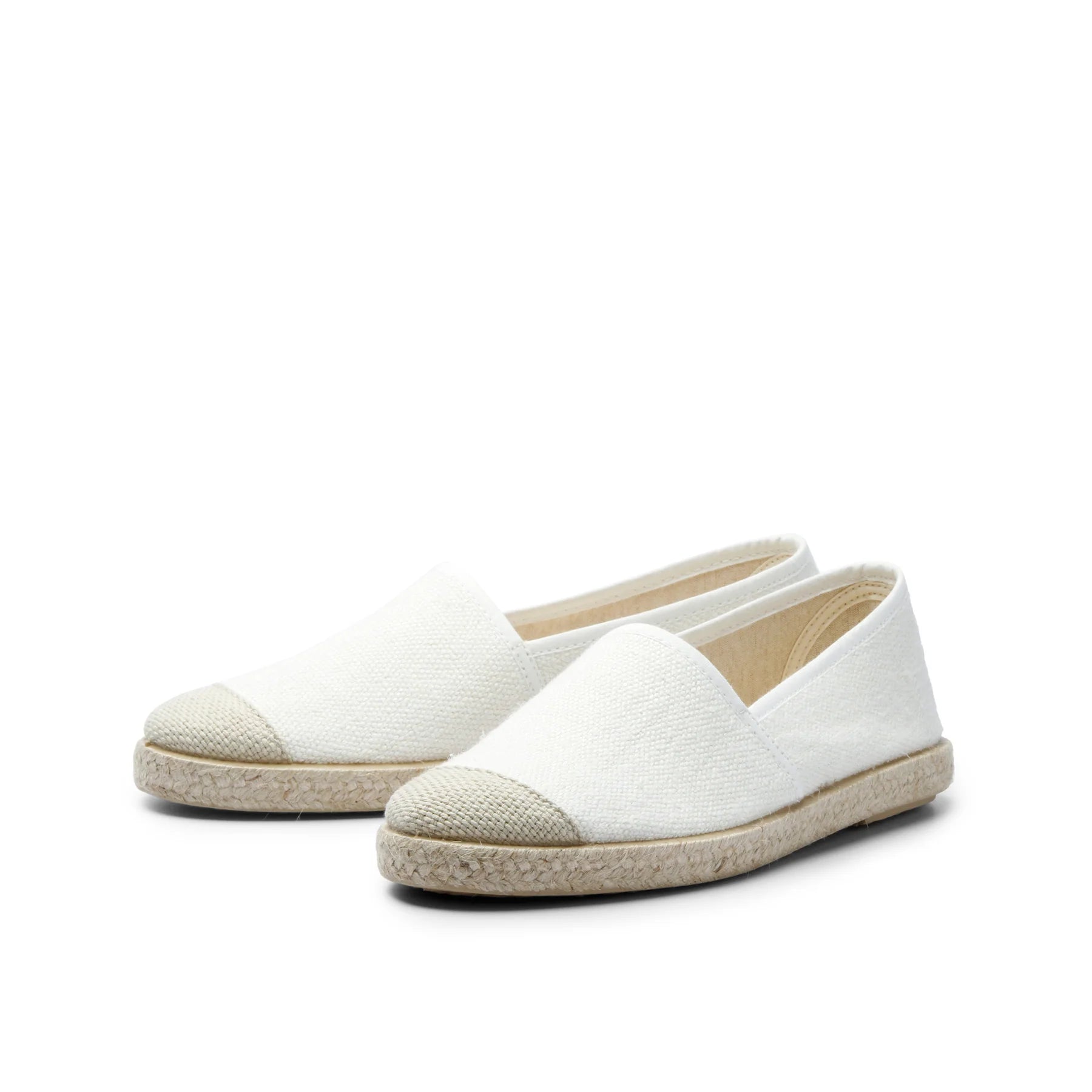 Weiße Espadrilles mit beigem Zehenbereich und Bastsohle auf weißem Hintergrund.