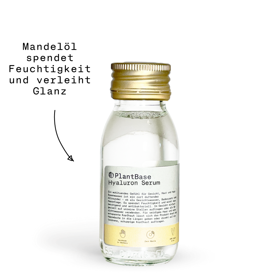 Eine durchsichtige Flasche mit goldenem Verschluss, die eine transparente Flüssigkeit mit der Aufschrift PlantBase Hyaluron Serum enthält. Das Etikett enthält Produktdetails und Symbole, die auf natürliche Inhaltsstoffe und eine vegane Zertifizierung hinweisen.