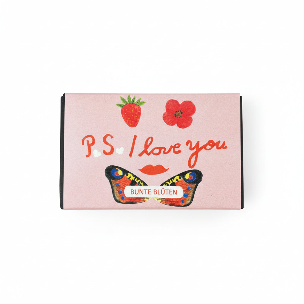 Eine rosafarbene Schachtel mit Abbildungen einer Erdbeere, einer roten Blume, roten Lippen und einem Schmetterling. Der Text lautet "P.S. Ich liebe dich" und "BUNTE BLÜTEN.".