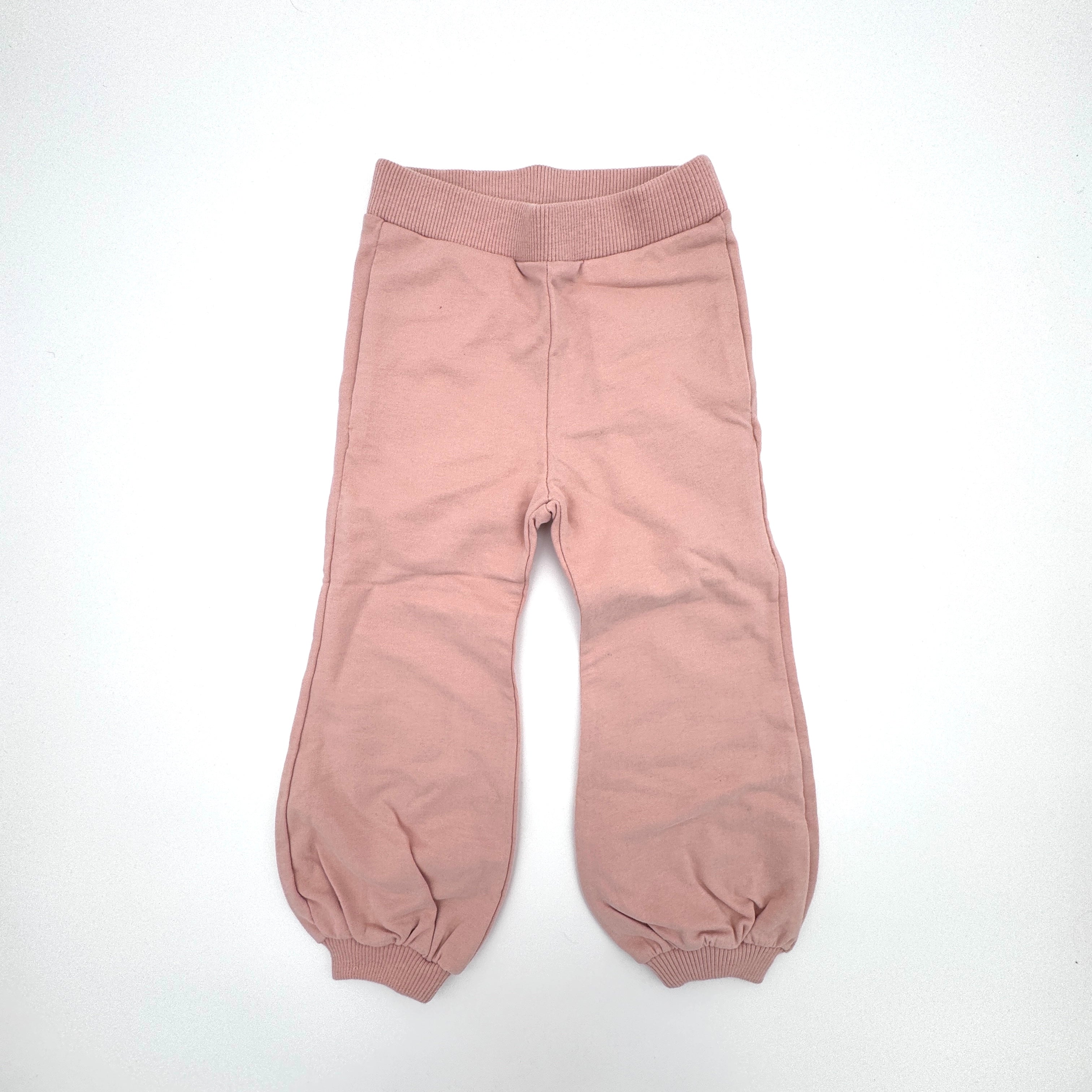 Hellrosa Hose für Kleinkinder oder Babys mit elastischem Bund und elastischen Bündchen an den Knöcheln, flach auf weißem Hintergrund.