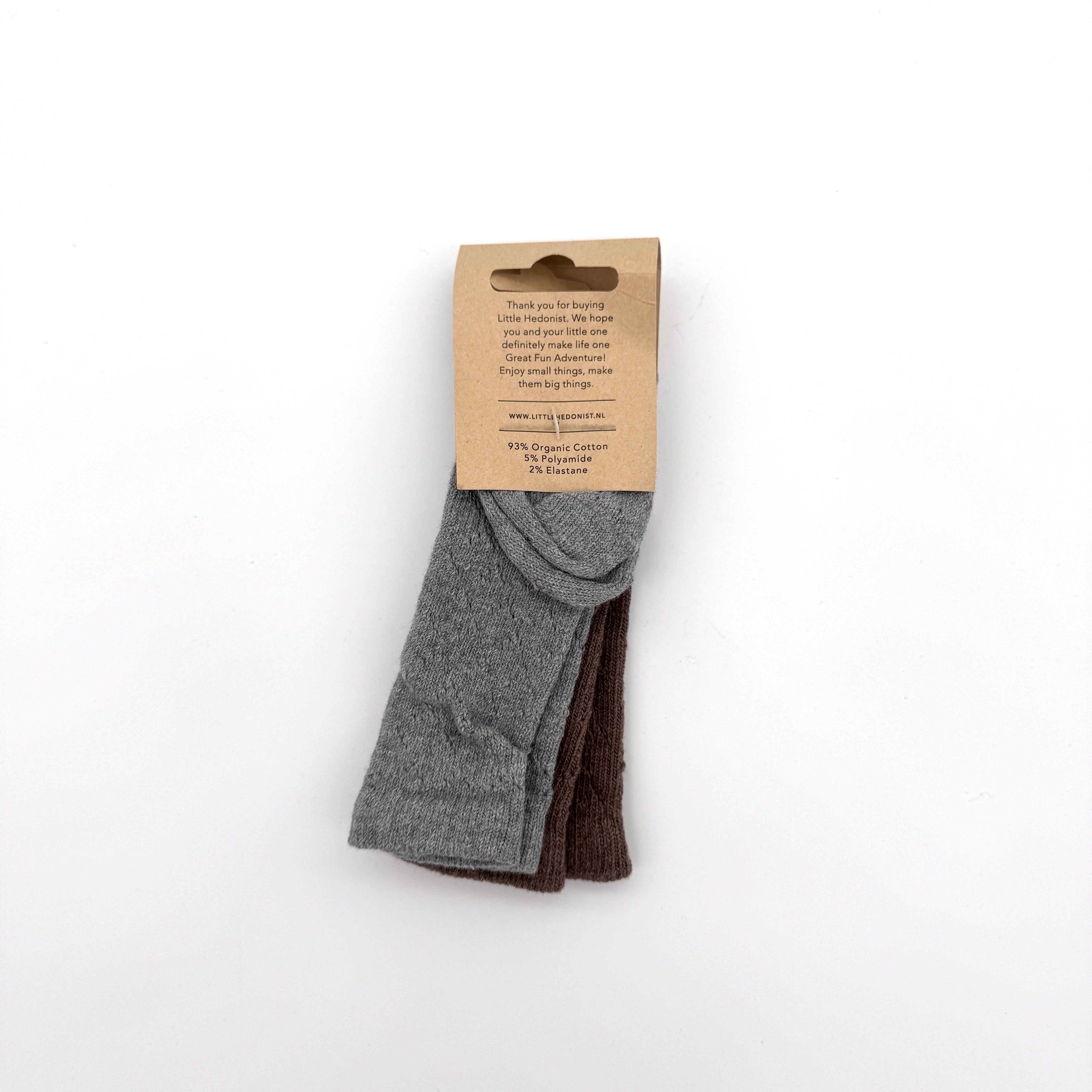 Zwei Paar gefaltete Socken, ein graues und ein braunes, werden von einem braunen Kartonetikett mit aufgedrucktem Text zusammengehalten, das auf einem schlichten weißen Hintergrund abgebildet ist.