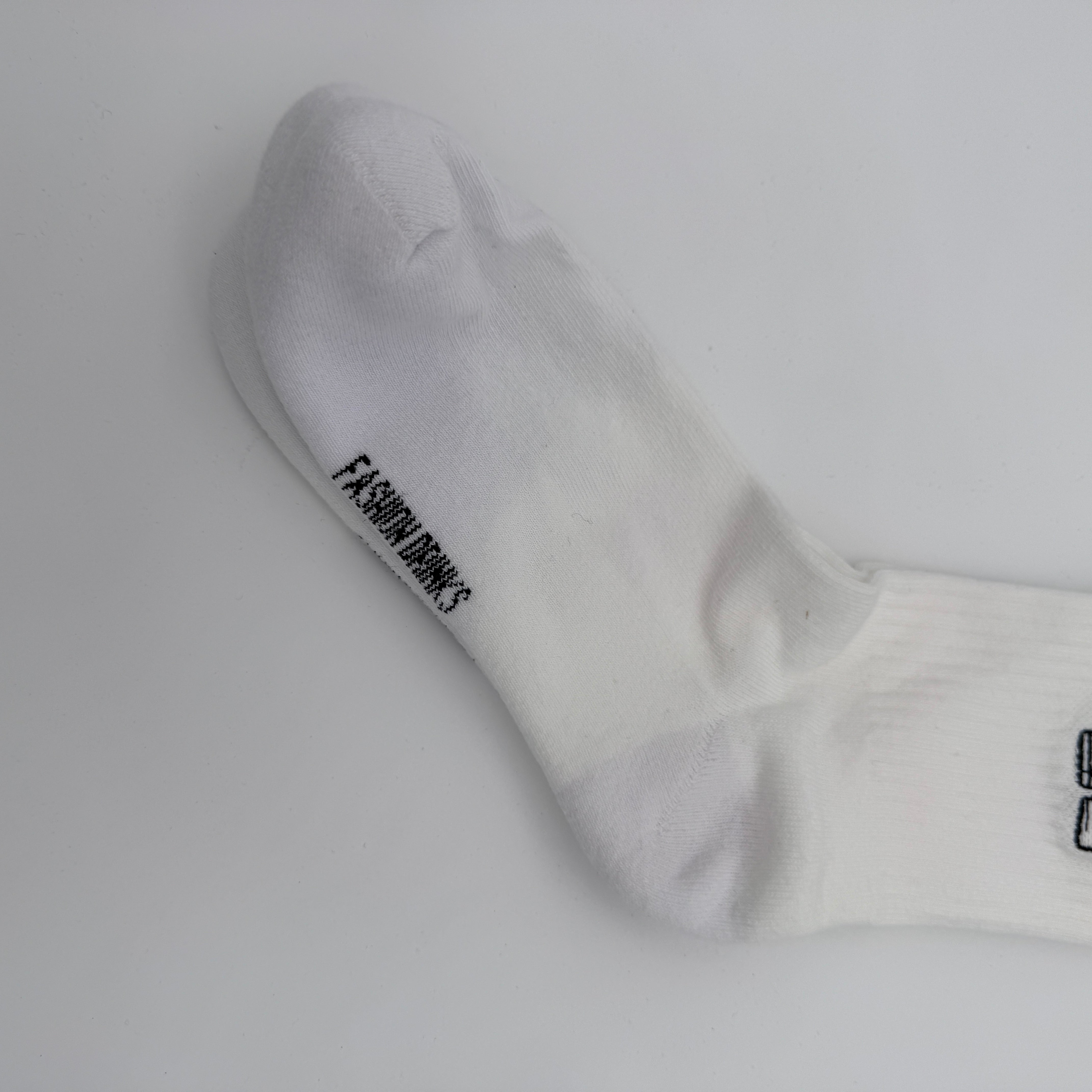 Eine weiße Socke mit schwarzem Text FASHION BROWS in der Nähe des Zehs auf weißem Hintergrund.