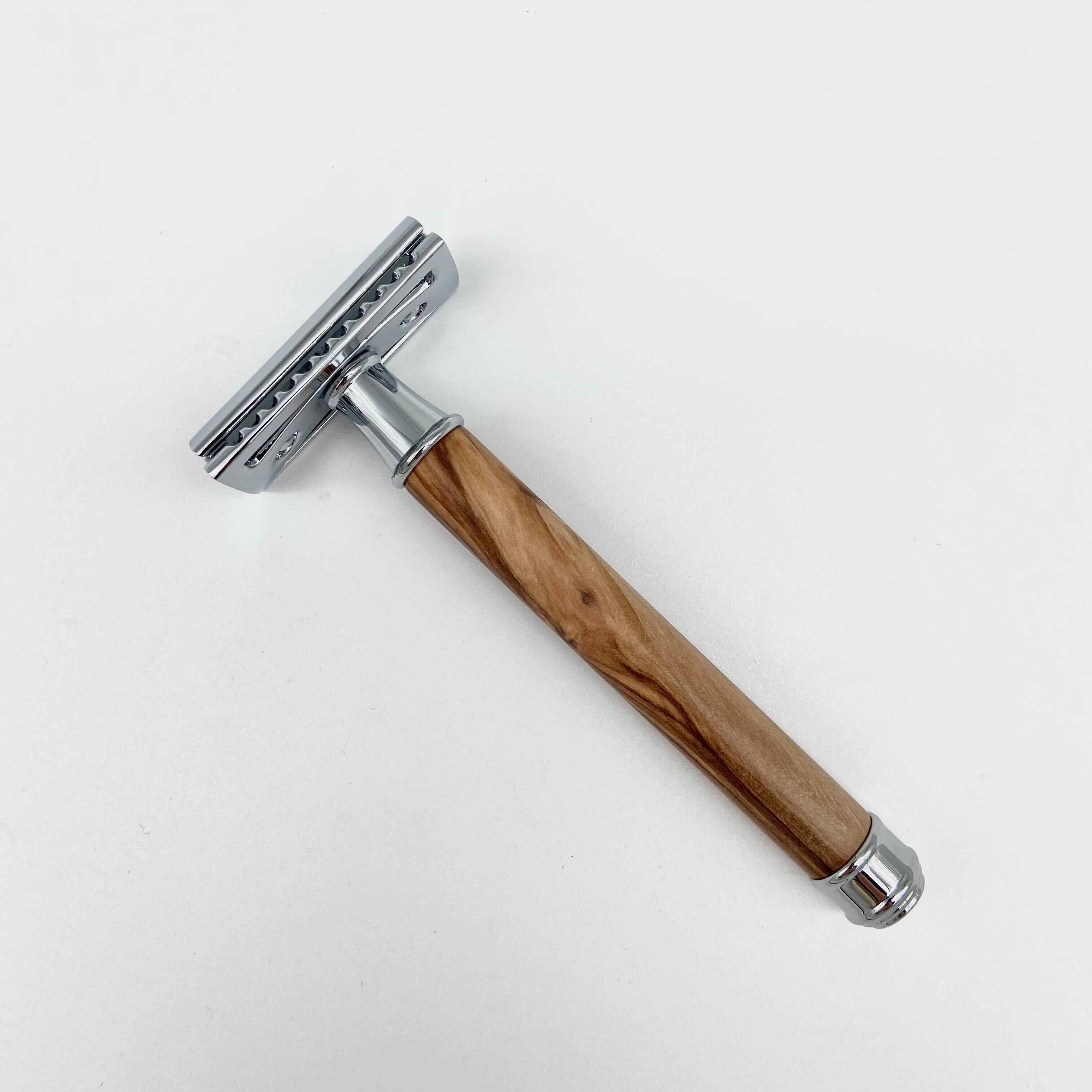 Ein Rasierhobel mit einem Holzgriff und metallischen Kopf liegt auf einer weißen Oberfläche.