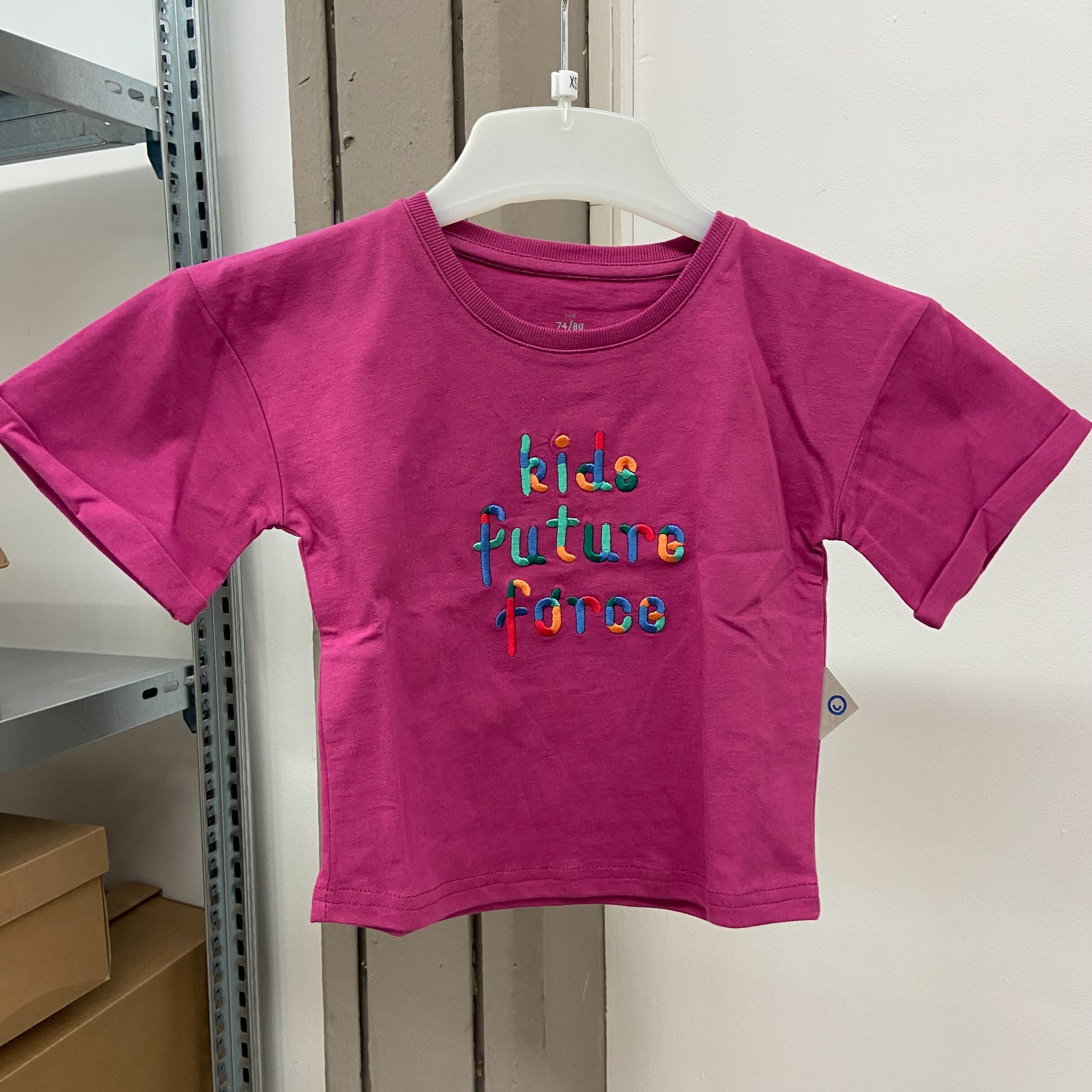 Rosa T-Shirt mit dem farbigen Schriftzug „kids future force“ auf einem weißen Kleiderbügel hängend.