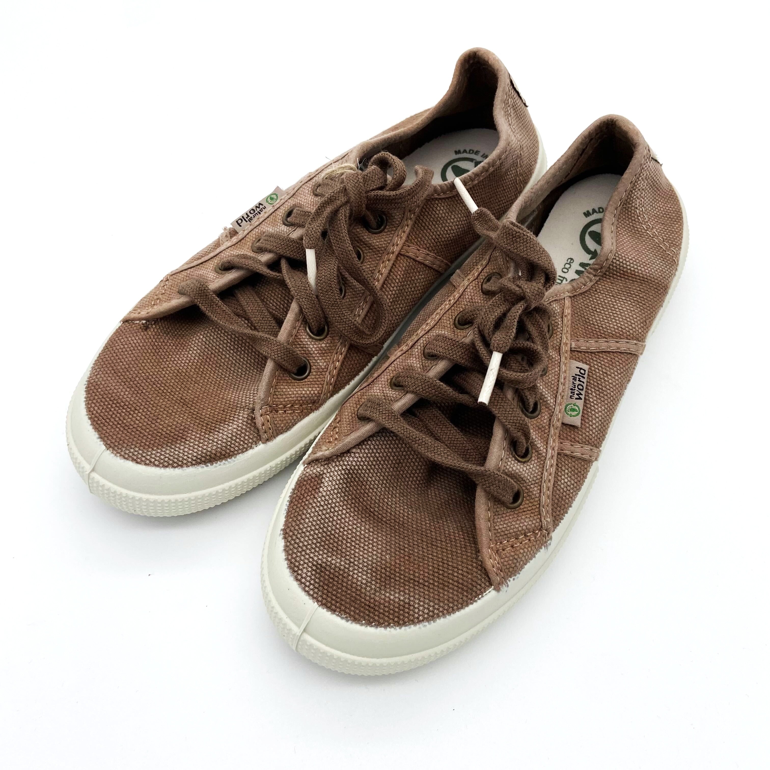 Ein Paar braune Sneakers mit weißen Sohlen und Schnürsenkeln auf weißem Hintergrund.