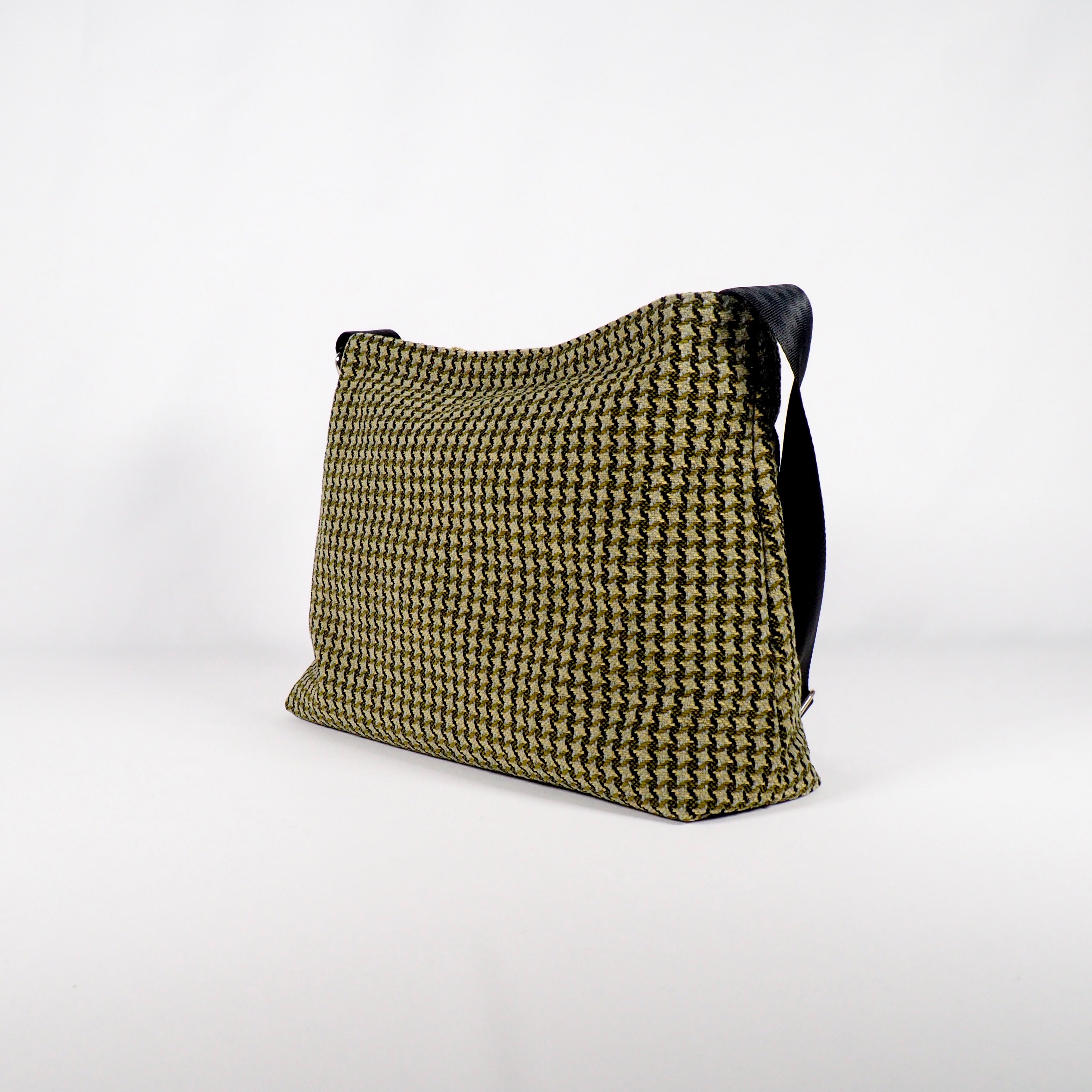 Braune Tasche mit schwarzem Träger und strukturiertem Muster, vor weißem Hintergrund.
