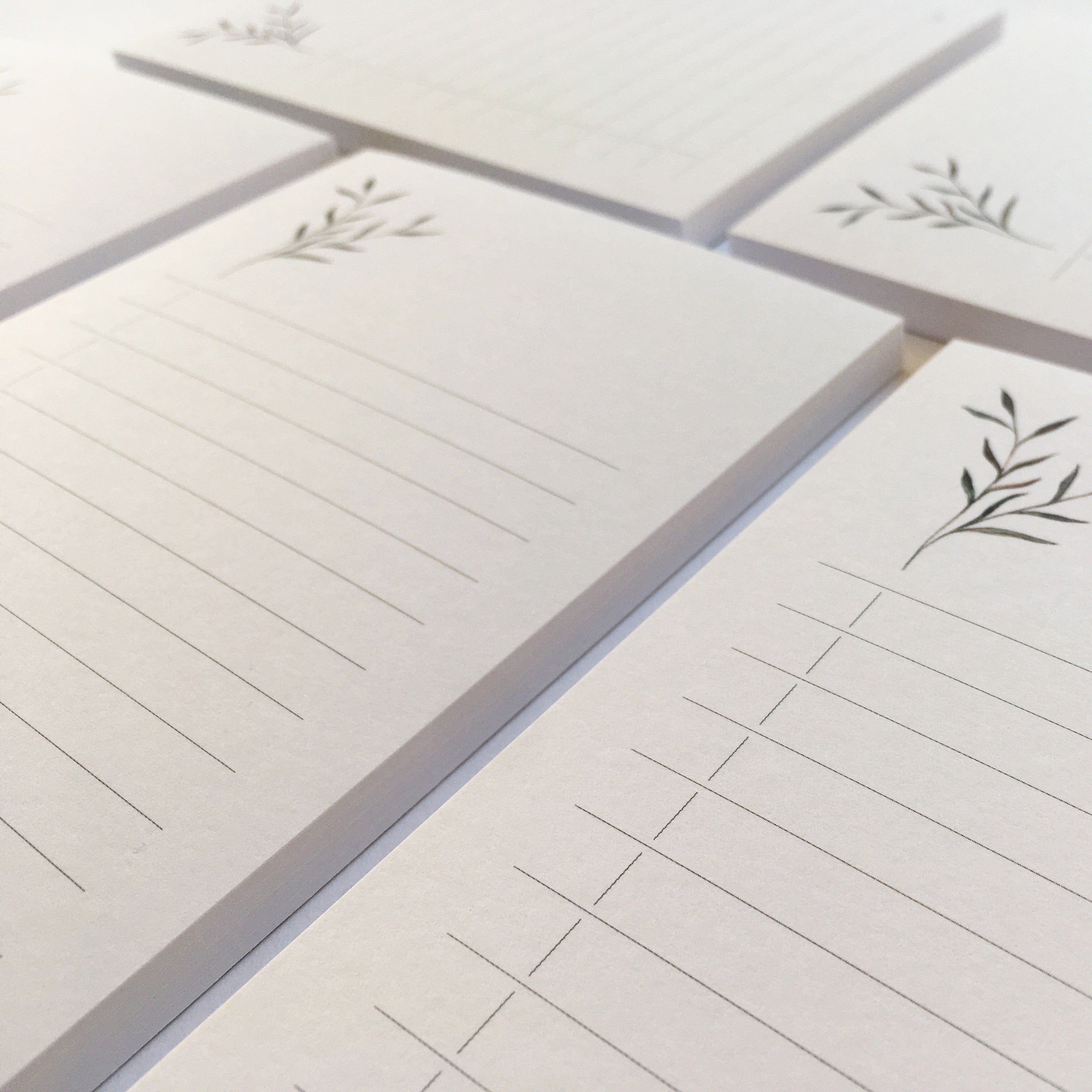 Gestapelte, linierte Notizblöcke aus Papier mit einem floralen Motiv in der rechten oberen Ecke.