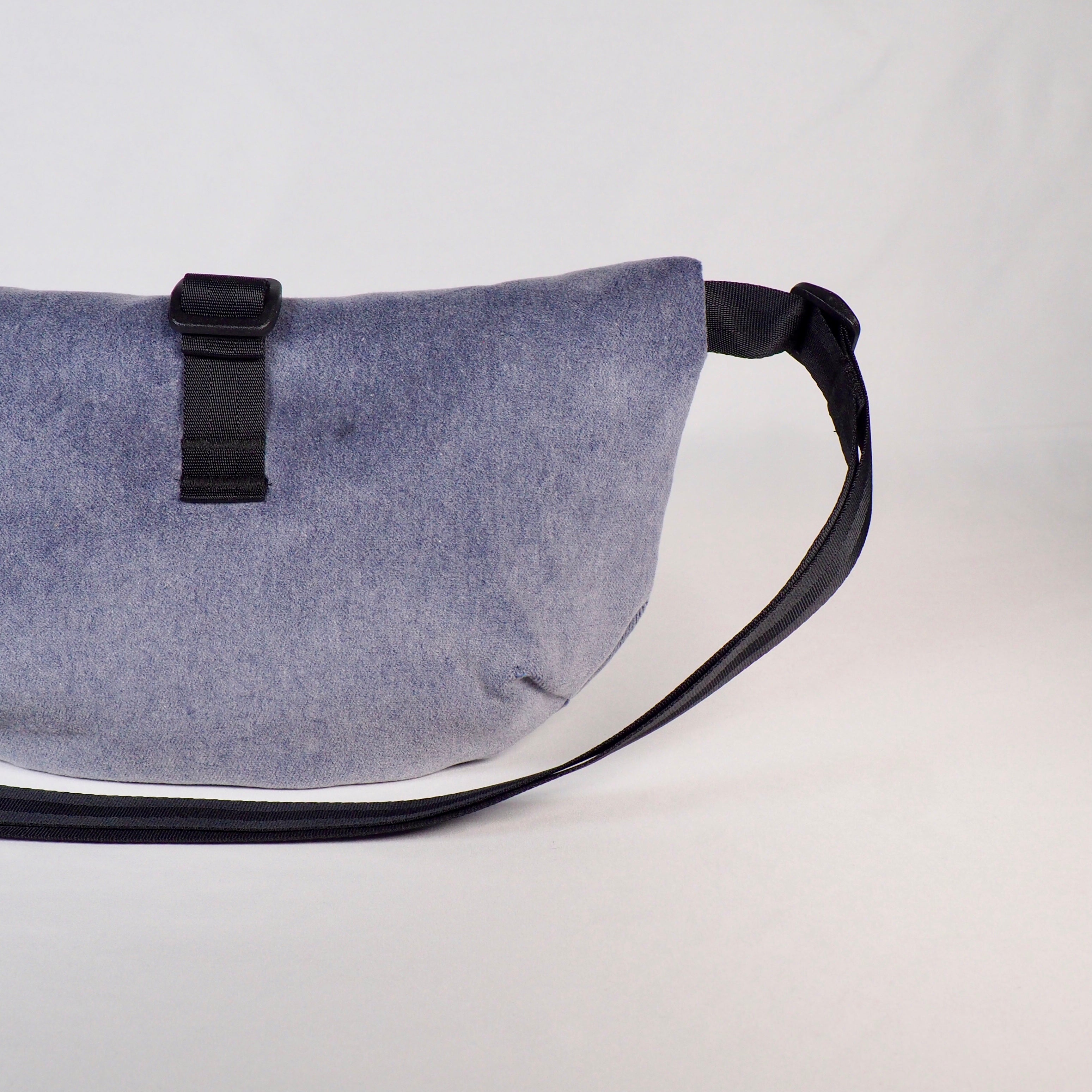 Graue Gürteltasche mit schwarzem Riemen und Schnalle vor einem neutralen Hintergrund.