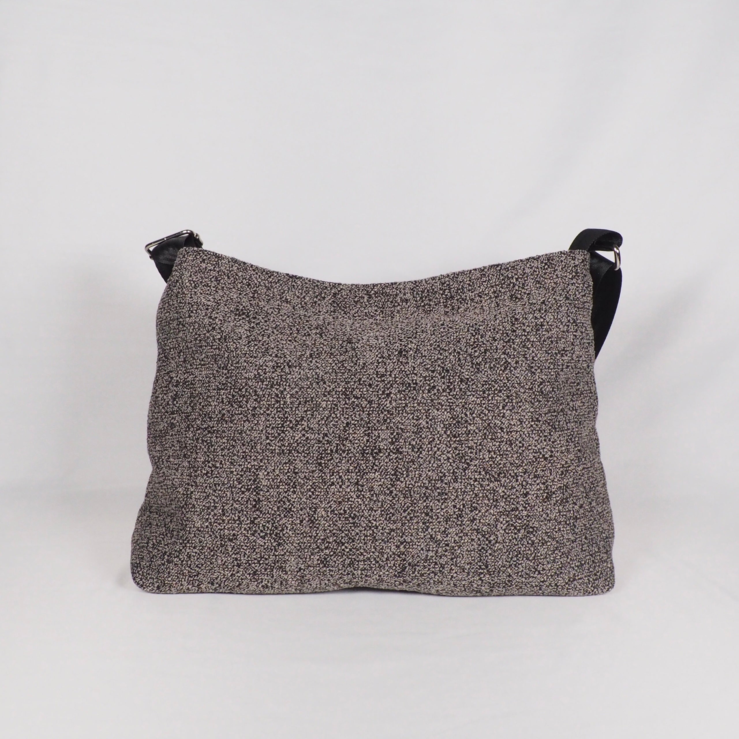 Graue Schultertasche mit feiner Textur vor weißem Hintergrund.